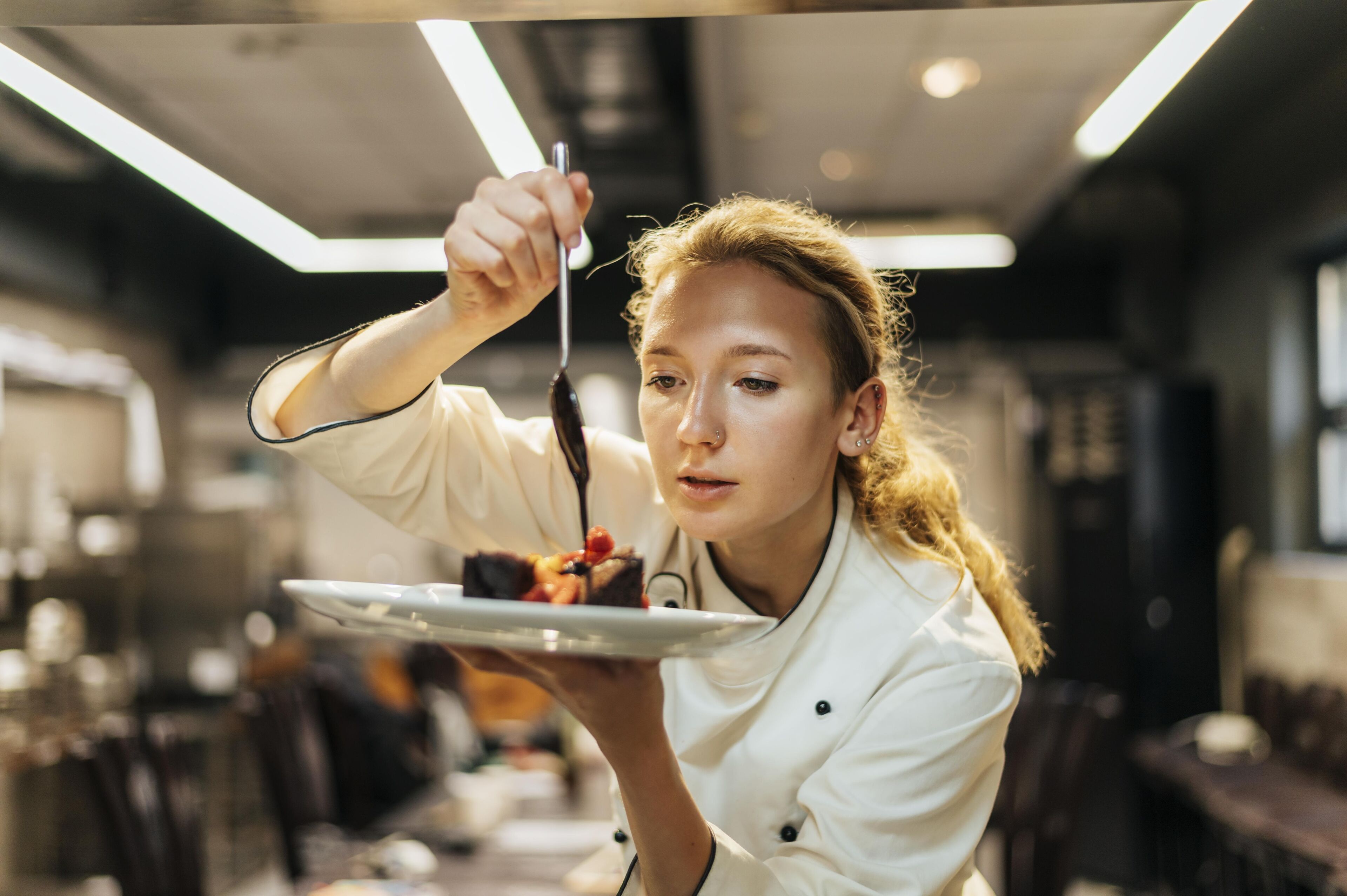 Una chef enfocada adorna meticulosamente un plato, demostrando la habilidad y atención al detalle en la cocina gourmet.