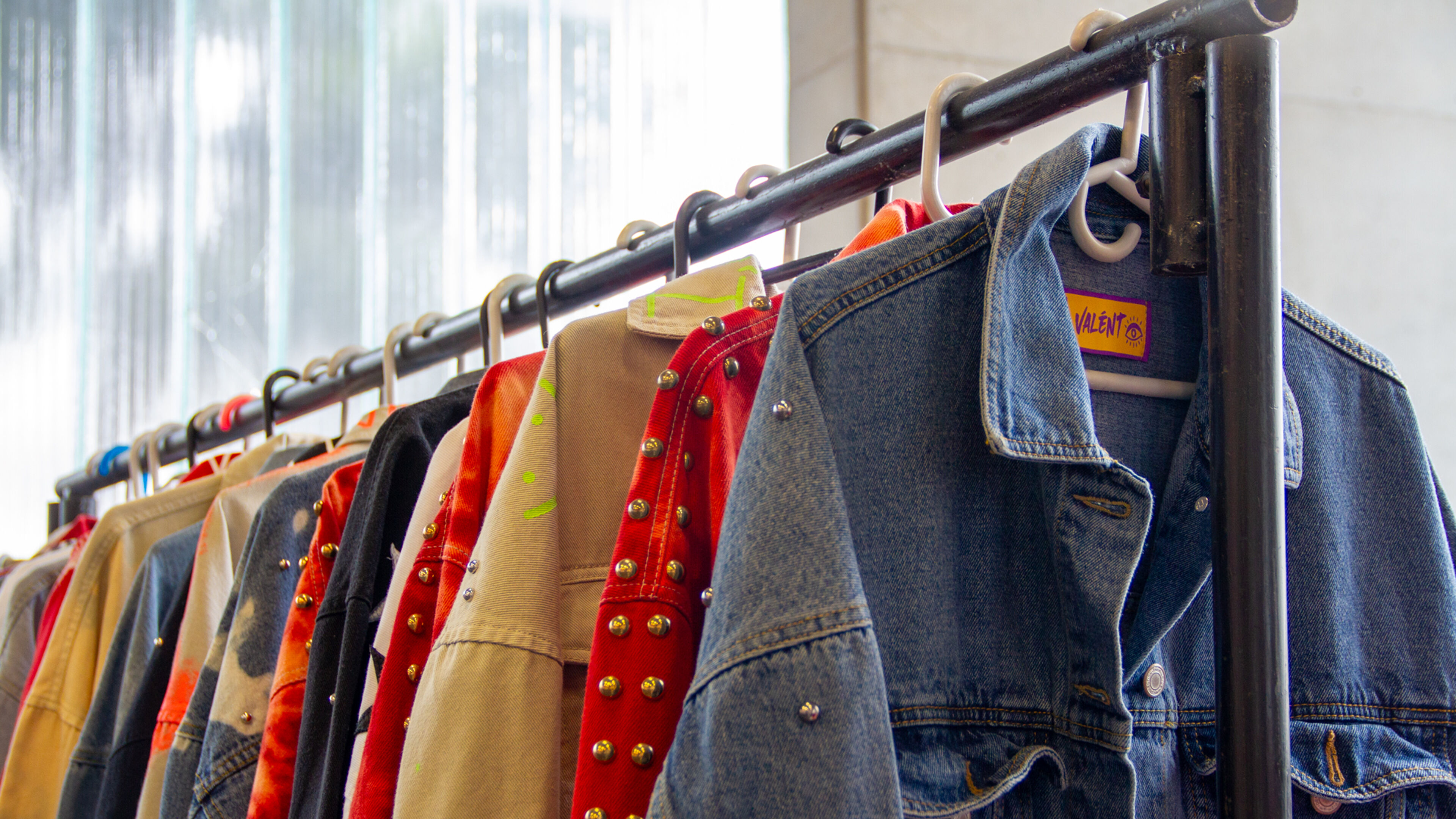 Una variedad colorida de chaquetas y camisas en un perchero, destacando una variedad de texturas y estilos.