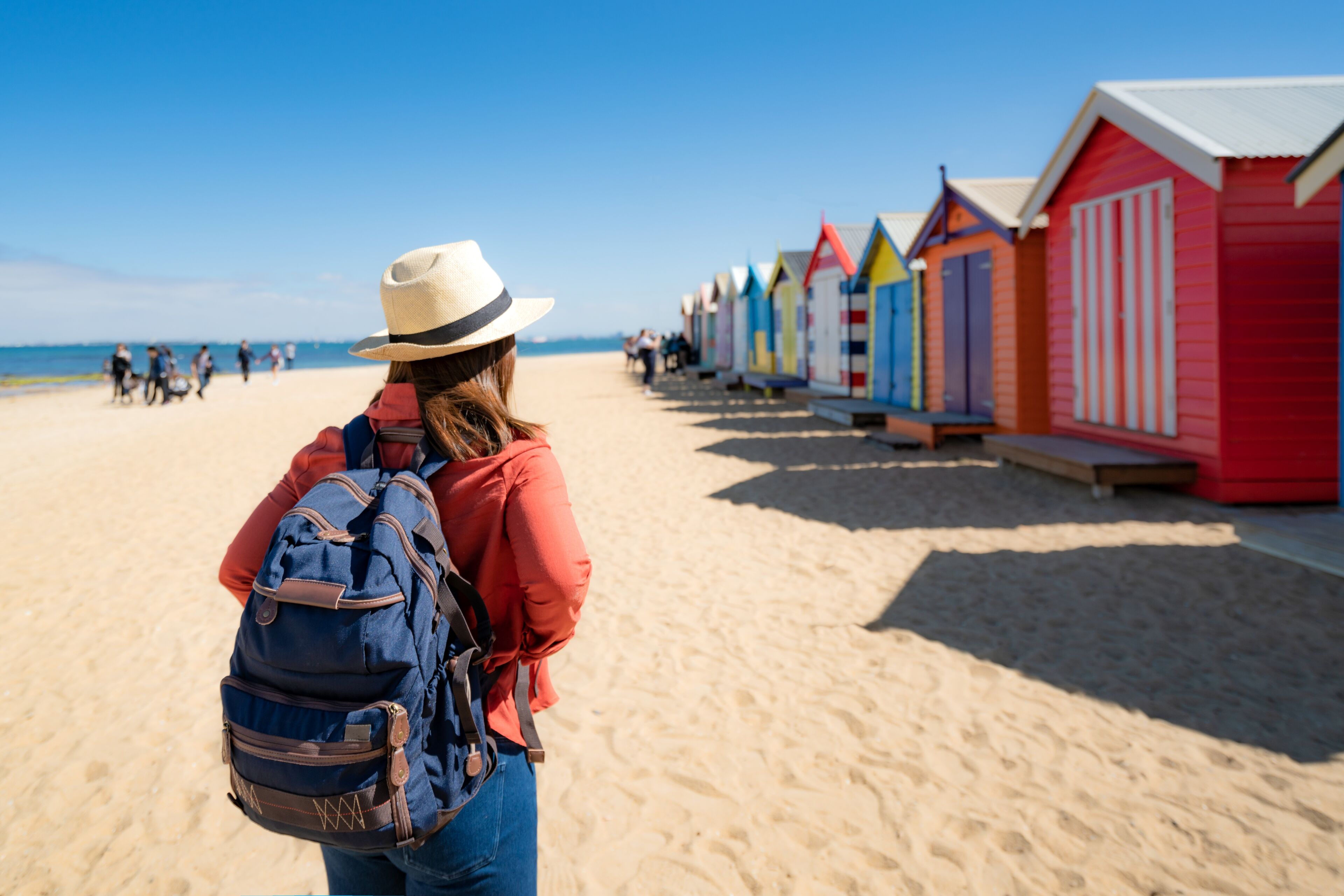 Asian woman traveler seesighting Brighton Bathing Boxes on white sandy beach at Brighton beach in Melbourne, Victoria, Australia.