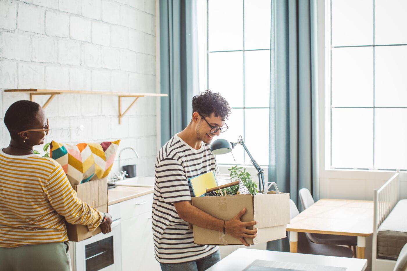 Flatmates moving in college dorm. They are caring boxes.