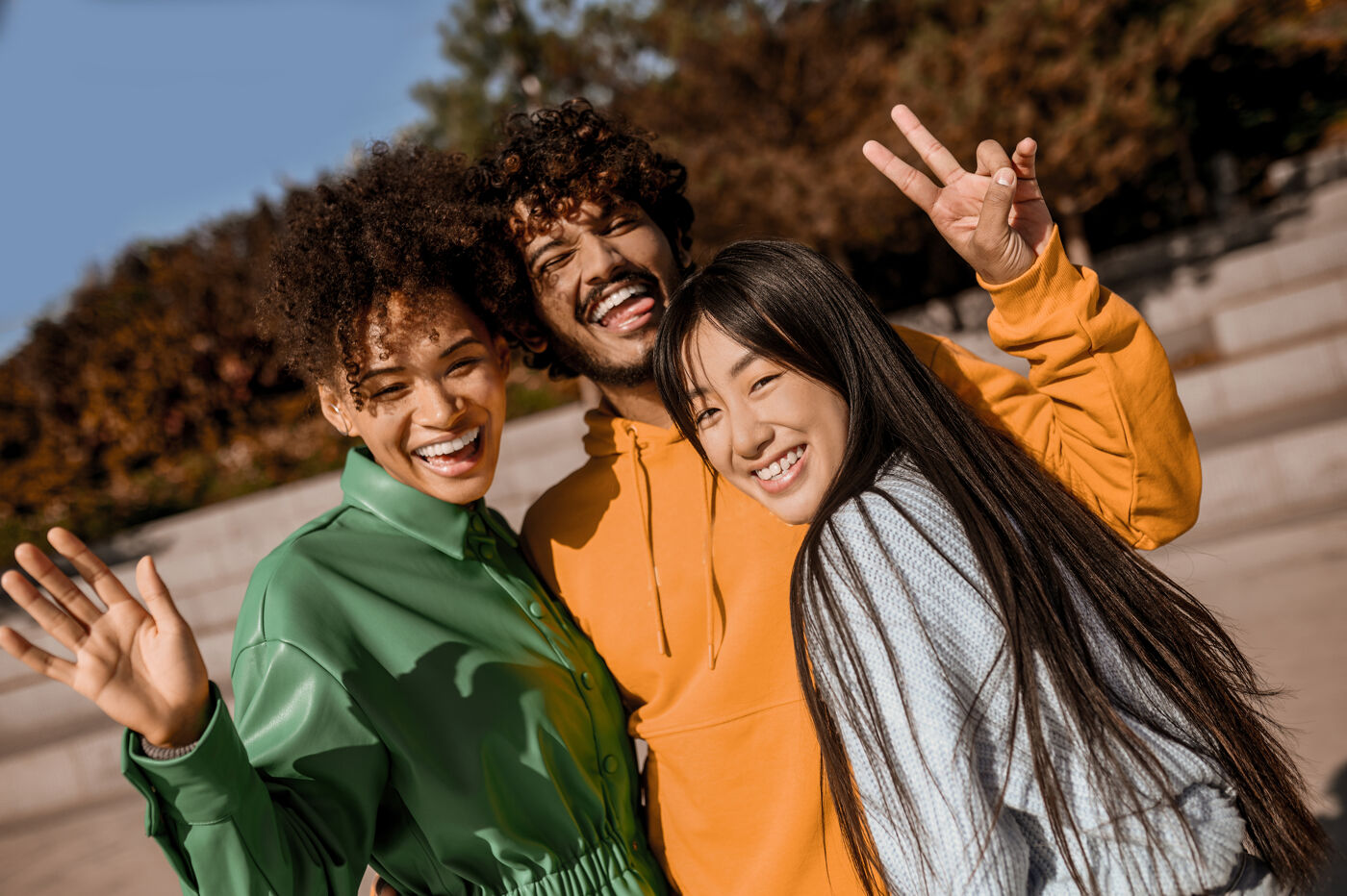 In the picture, there is a group of three people, two women and a man, posing together for a photo. They are standing close to each other, smiling, and enjoying their time together. The image captures a happy moment among friends or family members.