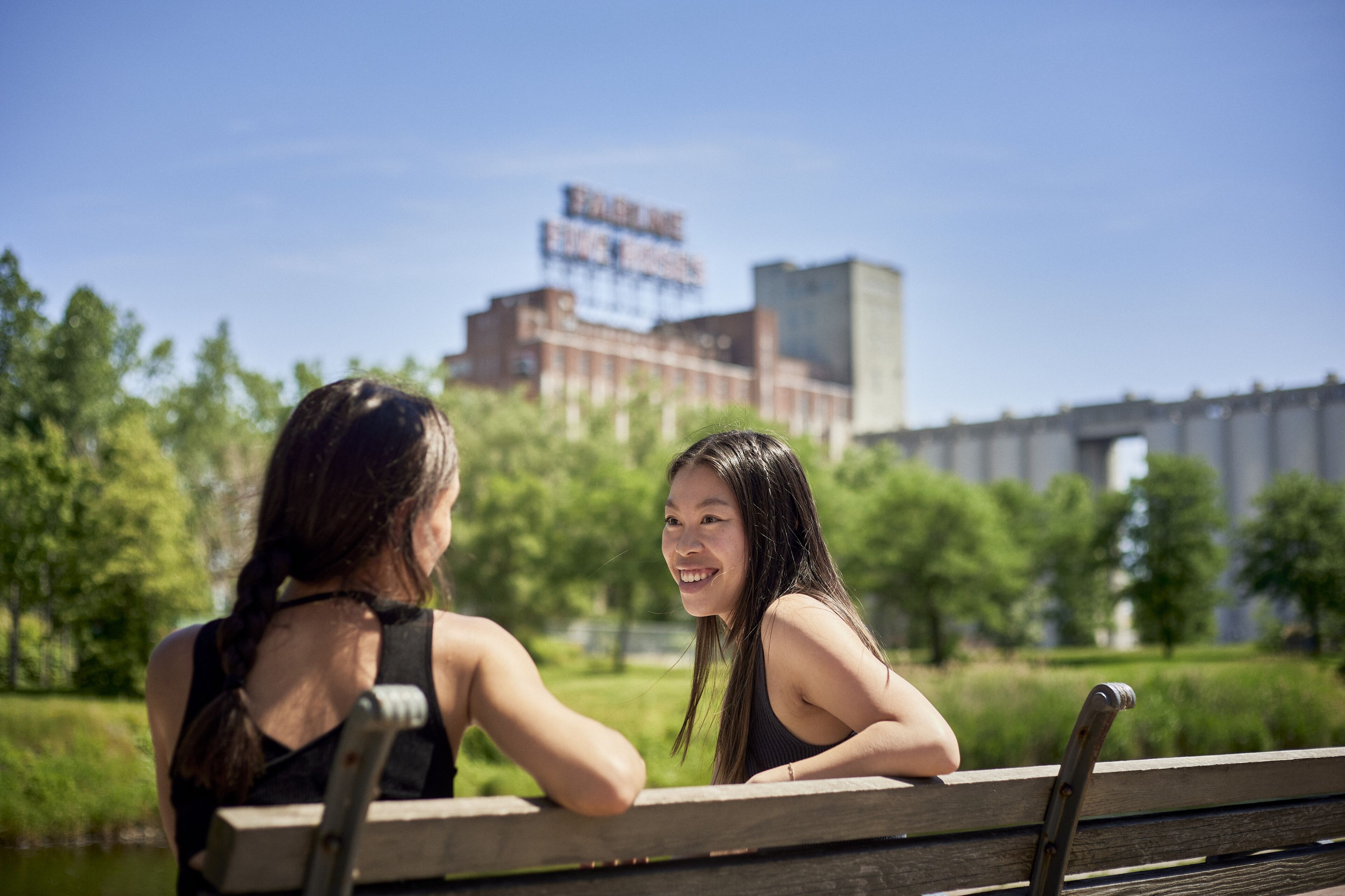 Two friends having a nice conversation on a park bench in the old port of Montreal in front of Five Roses