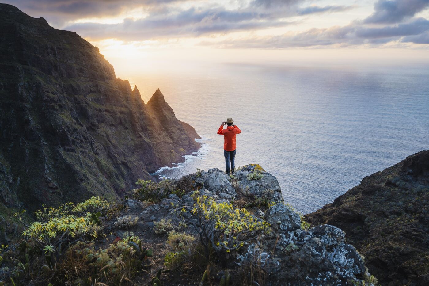 Man photographing the sunset on a cliff in Tenerife, Spain.