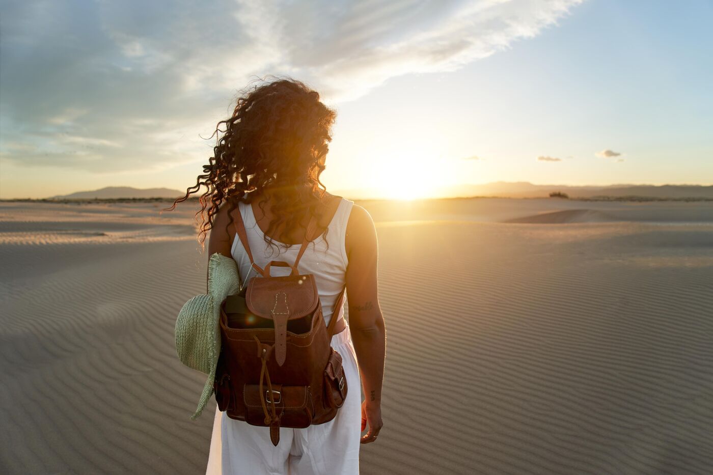  
Lovely image of African american young woman watching sunset at desert, enjoyment and satisfaction.