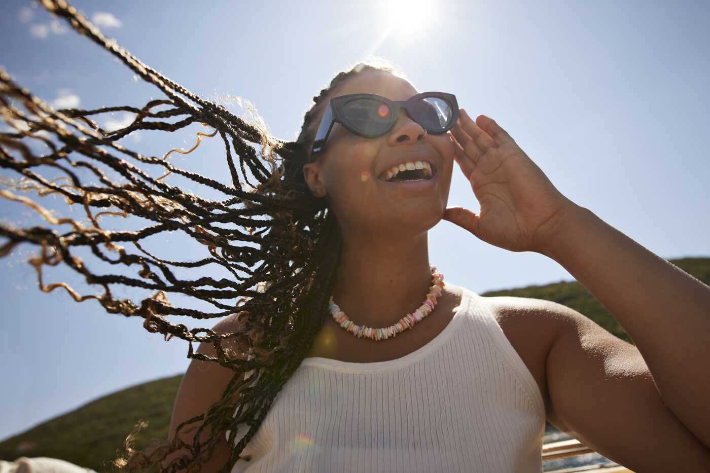 Mujer feliz ajustándose las gafas de sol en un día soleado