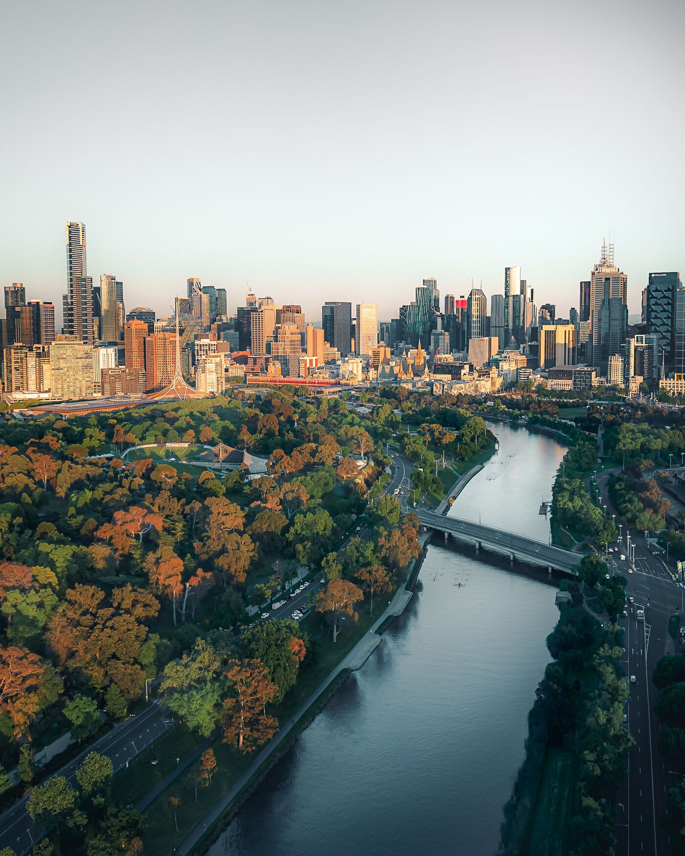 Aerial panorama of the city and its green spaces in the foreground of Melbourne at first light.