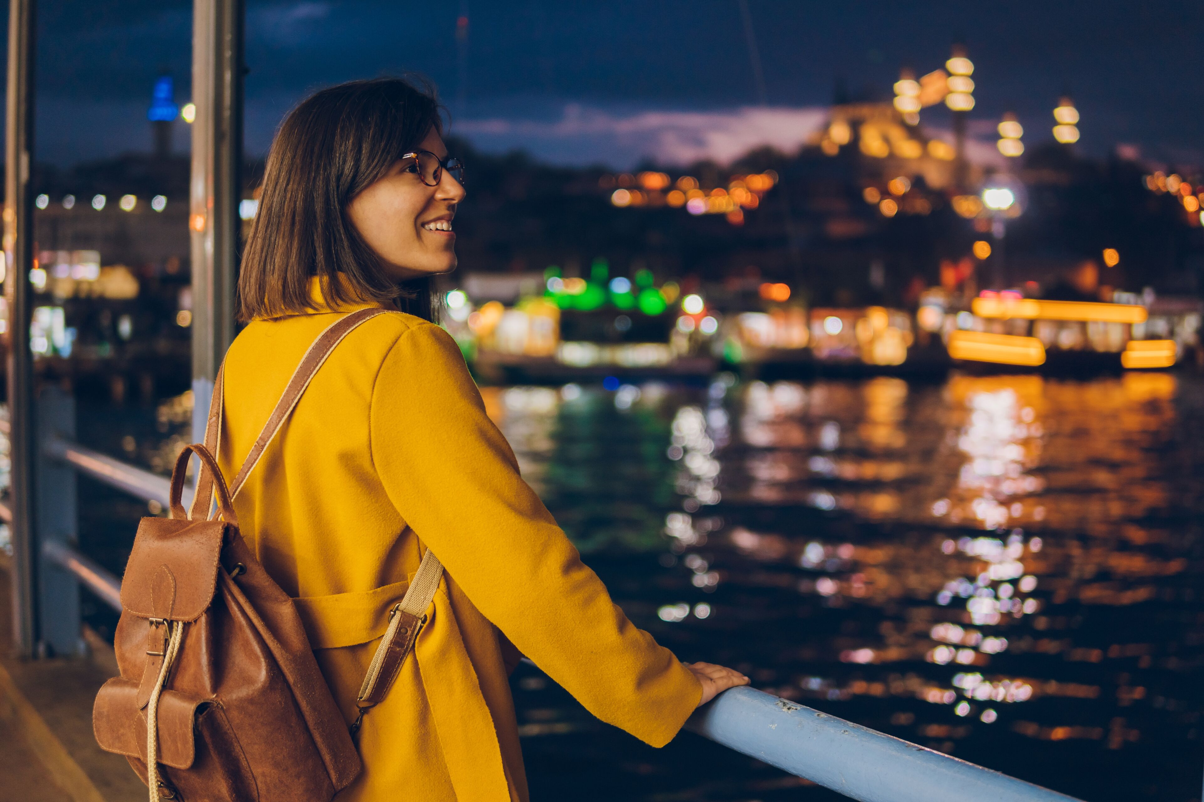 Une jeune femme regarde Istanbul la nuit depuis un quai
