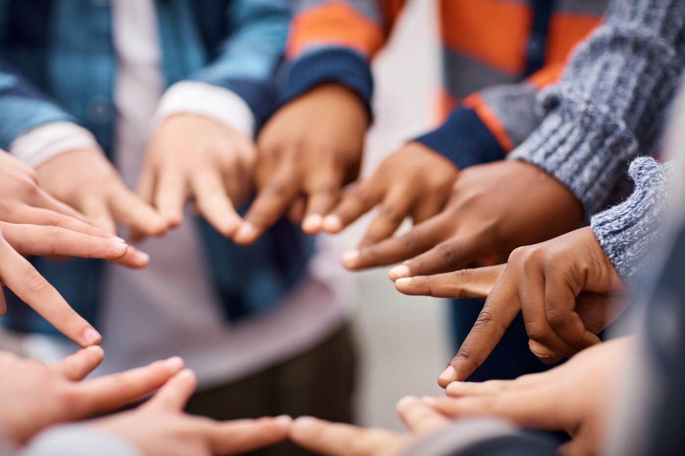 Closeup shot of a group of unrecognizable elementary school kids making peace signs in a huddle