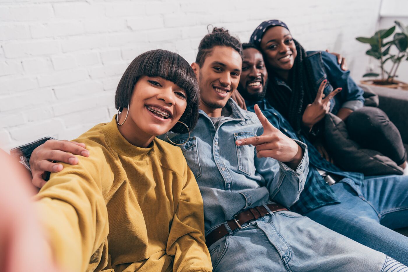 young mixed race woman taking selfie with multiethnic friends doing peace gesture