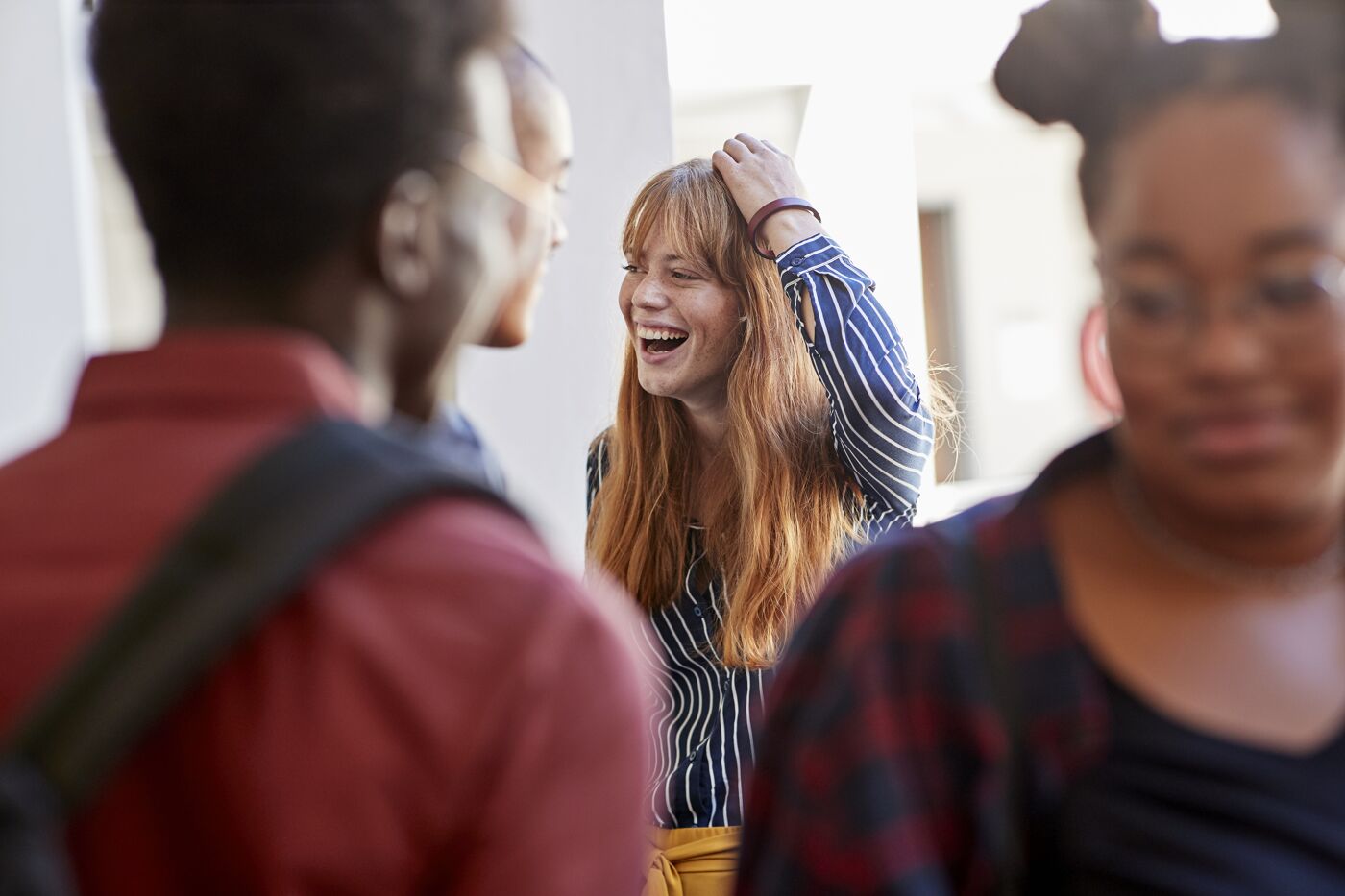 Cheerful student with hand in hair amidst friends