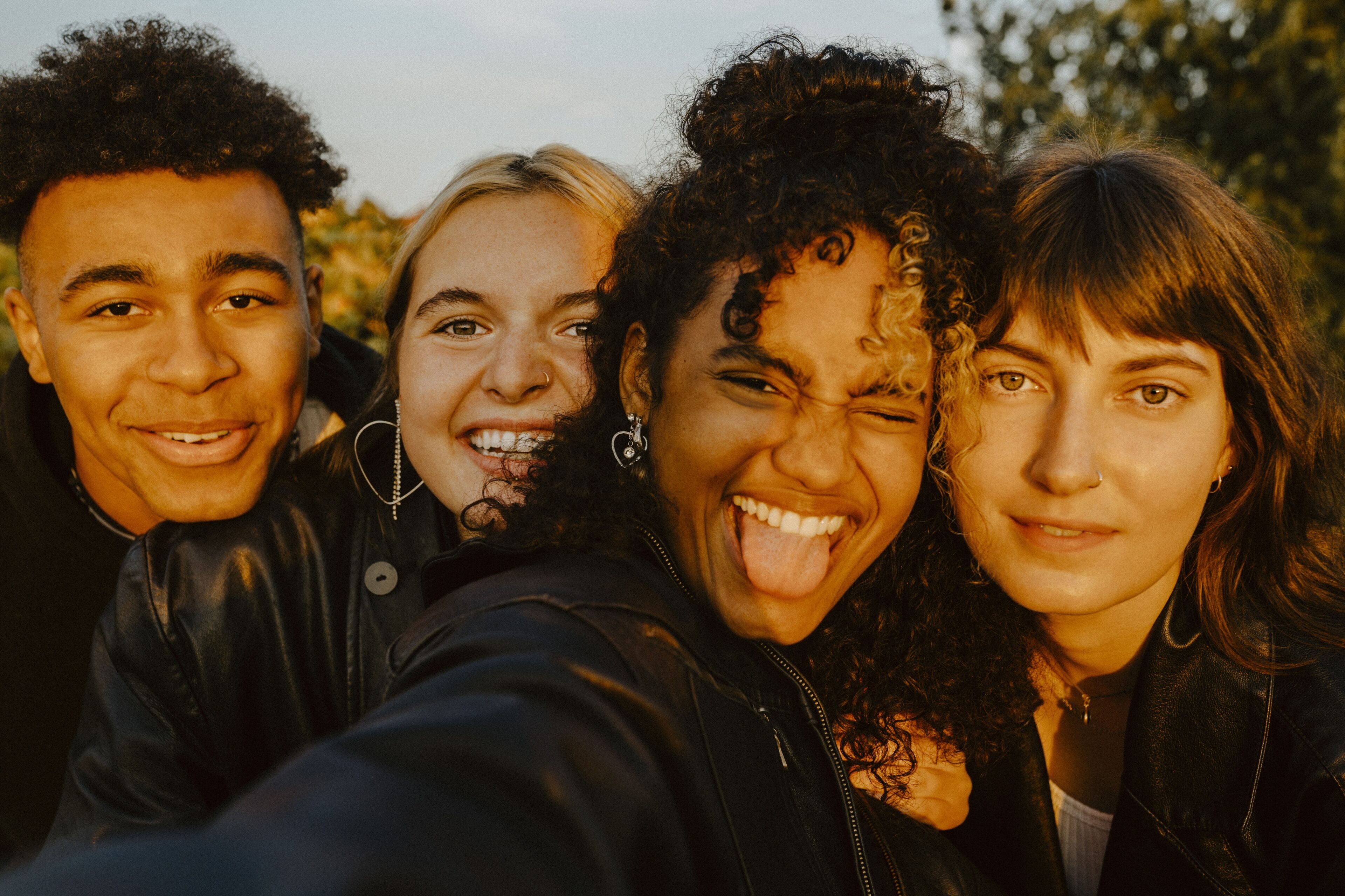 Cheerful friends taking selfie outdoors during sunset