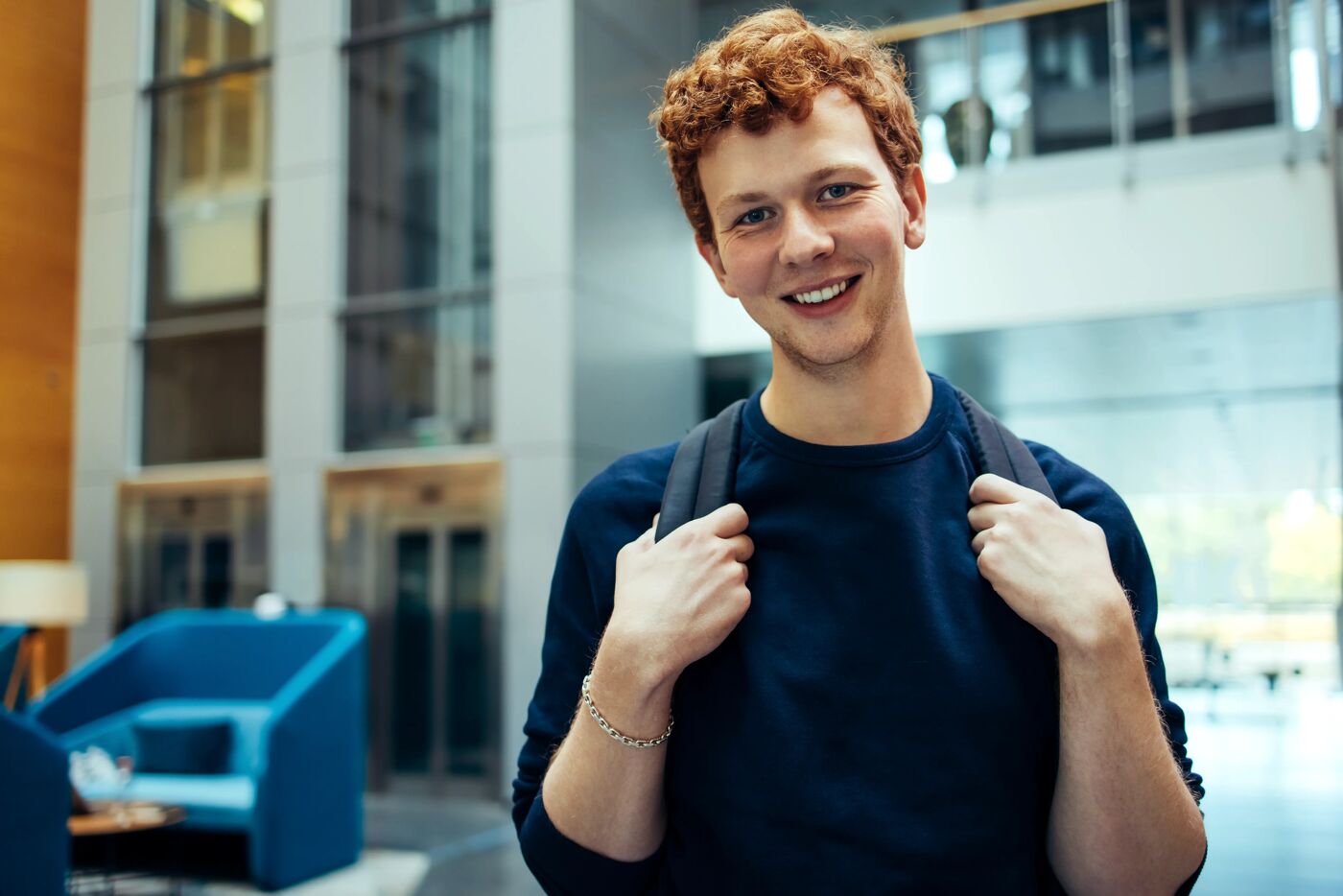 Smiling Student with Backpack in Modern Building