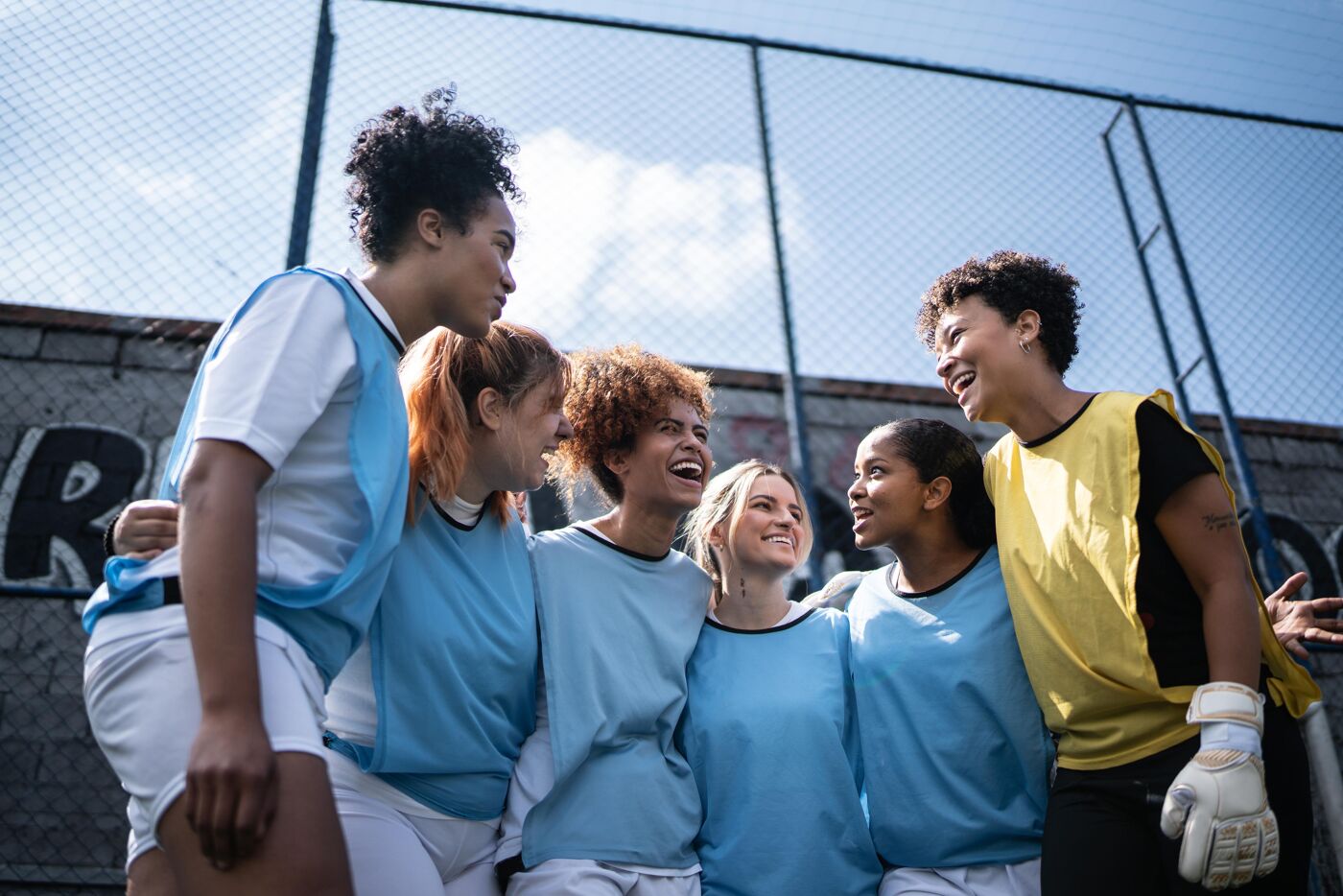 Happy female soccer team arm around  