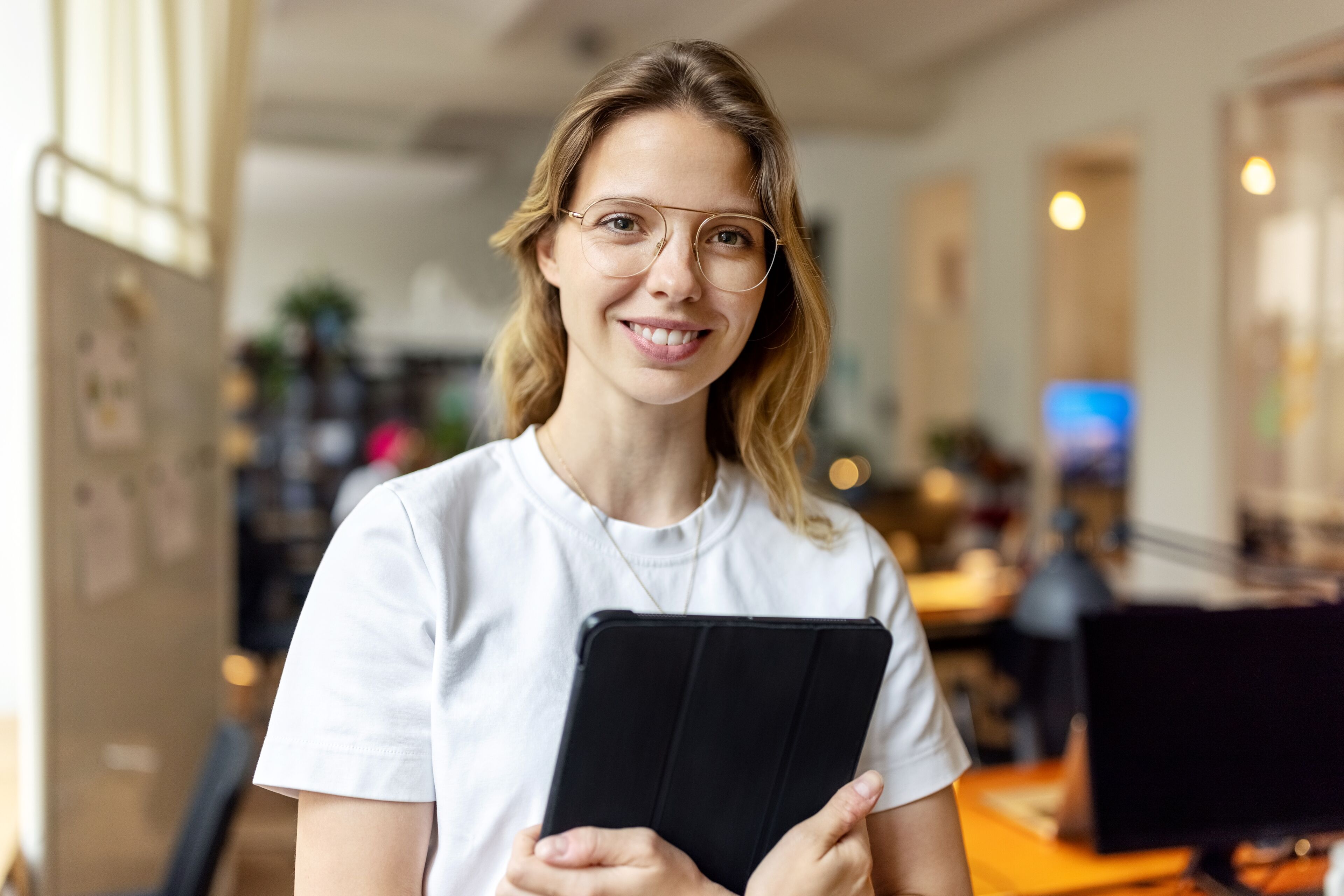Portrait of a happy young businesswoman in office. Female wearing casuals holding digital tablet looking at the camera.
