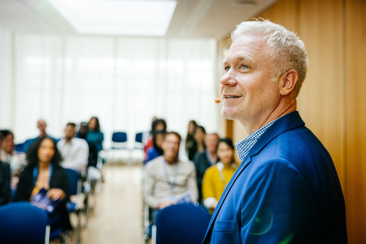 A speaker at a business conference looking back while giving a presentation to participants.