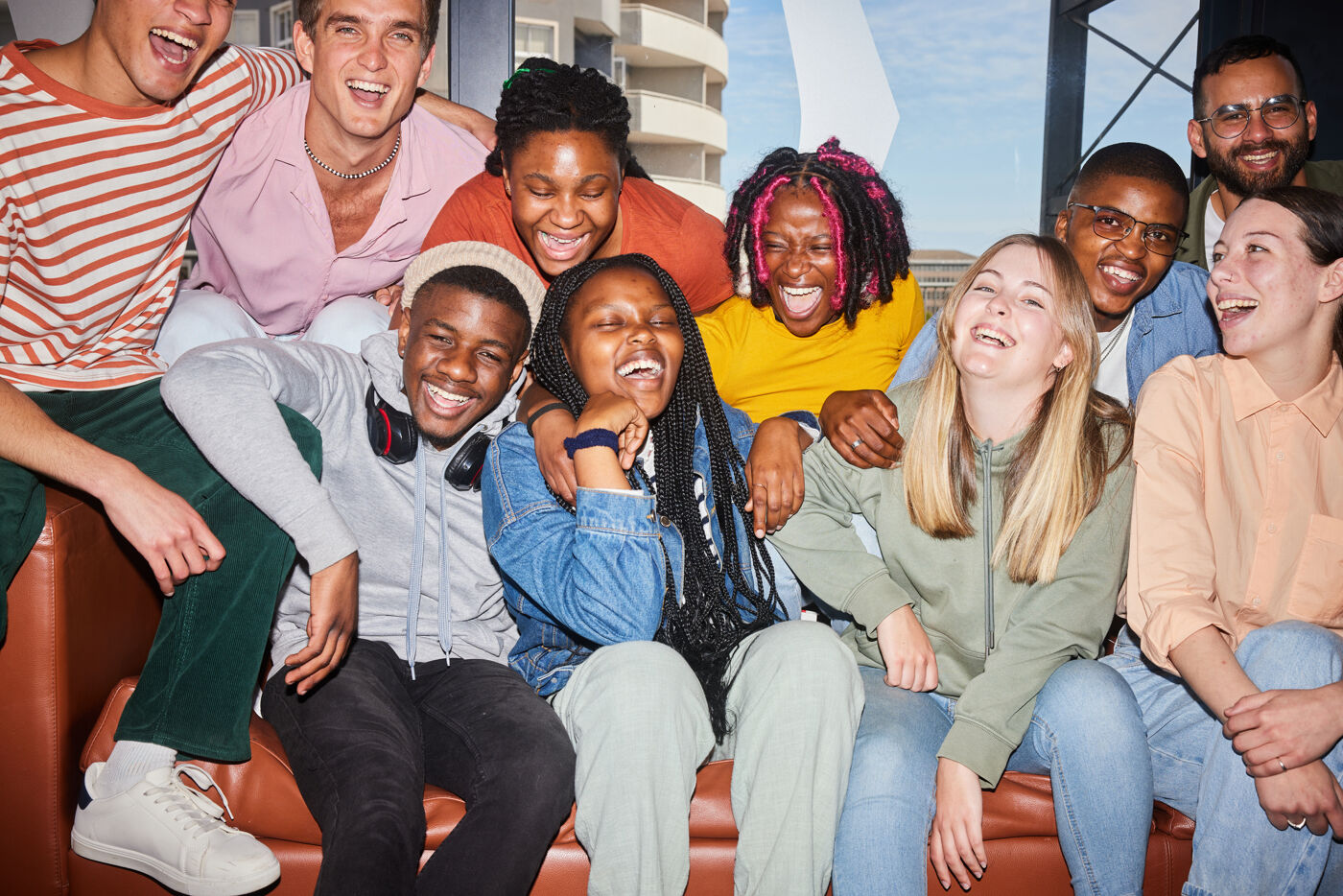 Diverse young college students and their teach laughing on a sofa at school