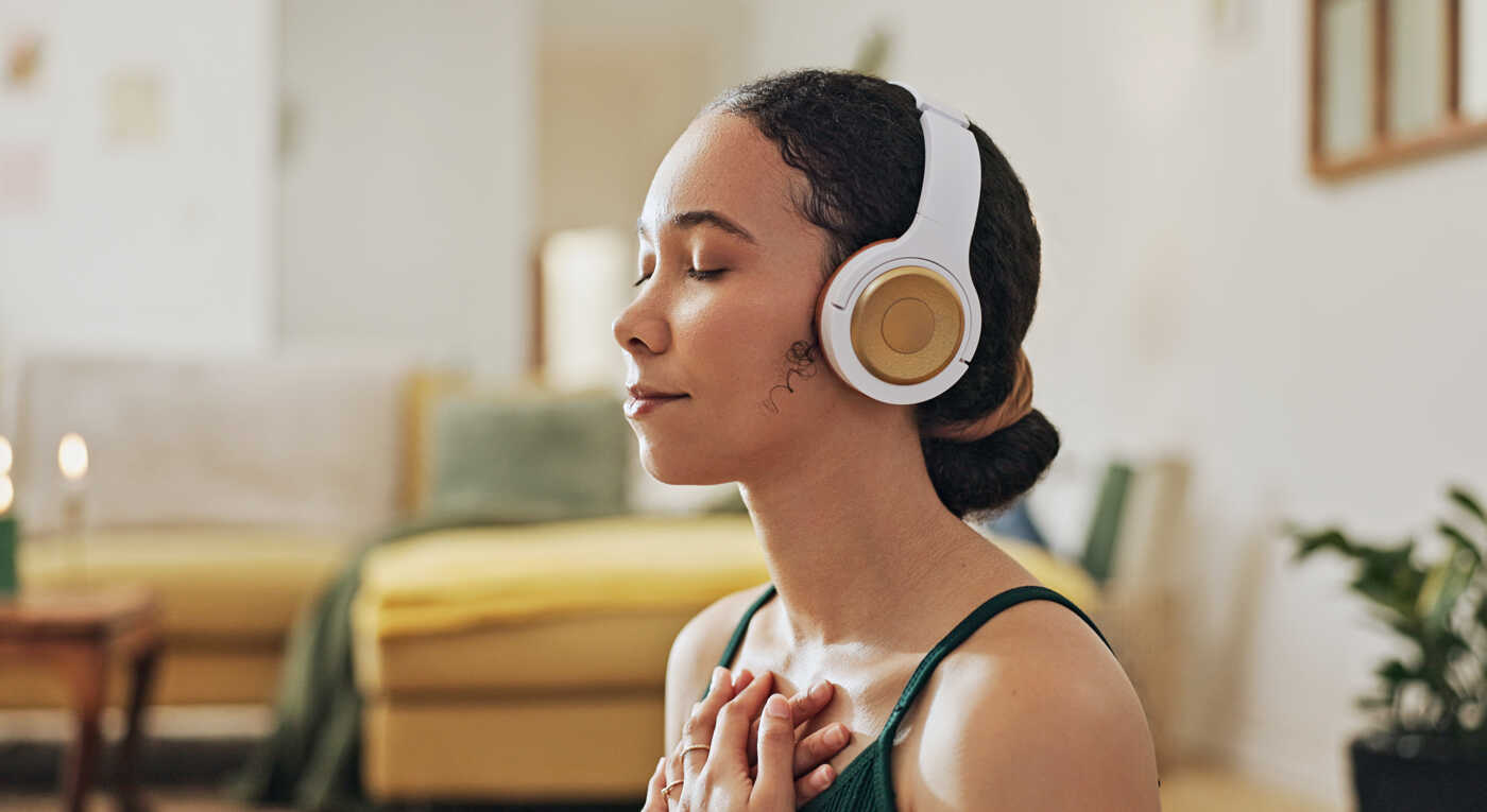 Mujer, meditación y yoga con auriculares escuchando música tranquila, ejercicio holístico y paz en la sala de estar. 