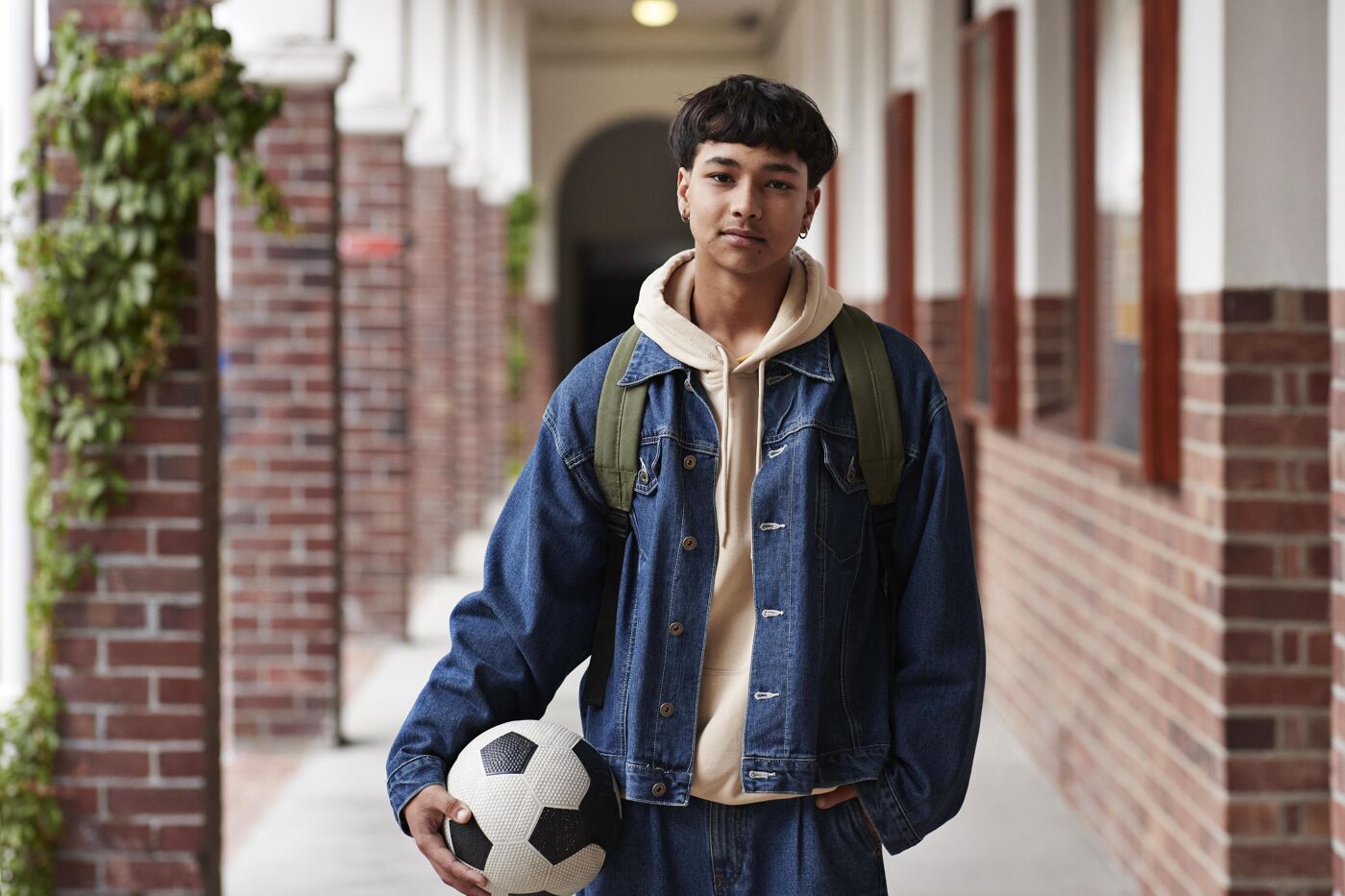 The picture features a young man holding a soccer ball and posing for a photo.