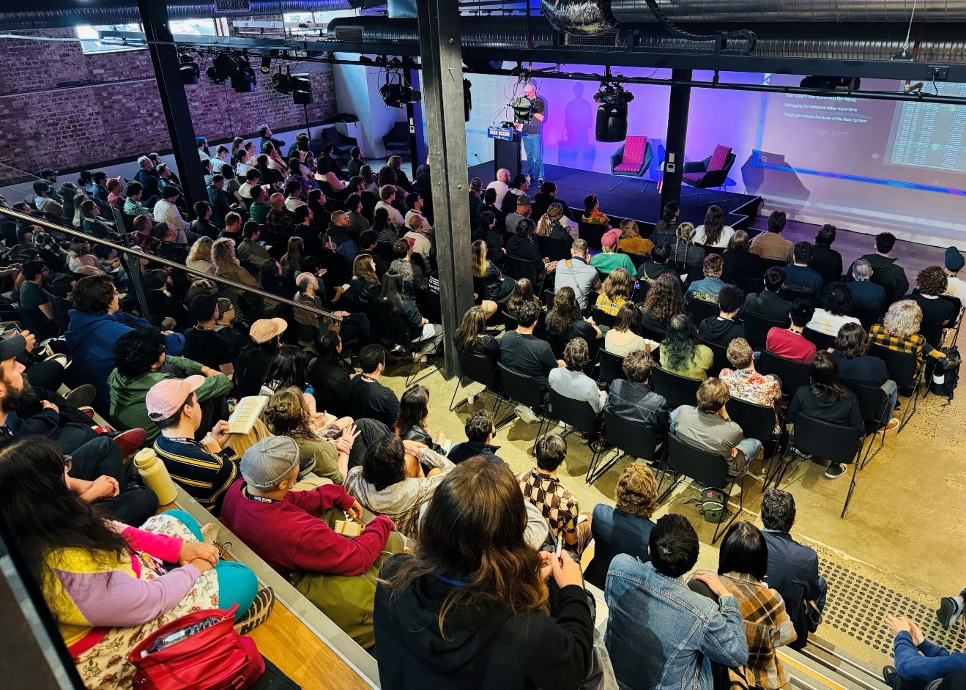 Large Audience Attending a Presentation in an Industrial-Style Venue