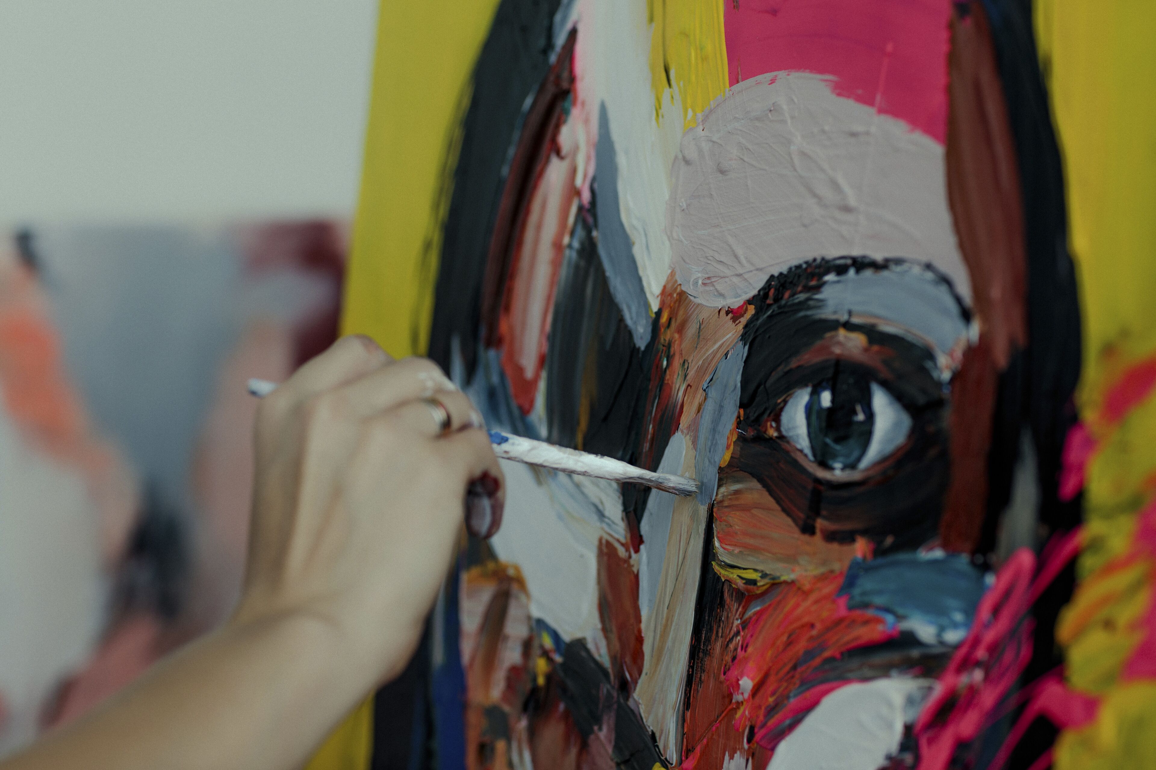 Main d'un artiste appliquant des peintures à l'huile vibrantes sur une toile, se concentrant sur un détail de l'œil.