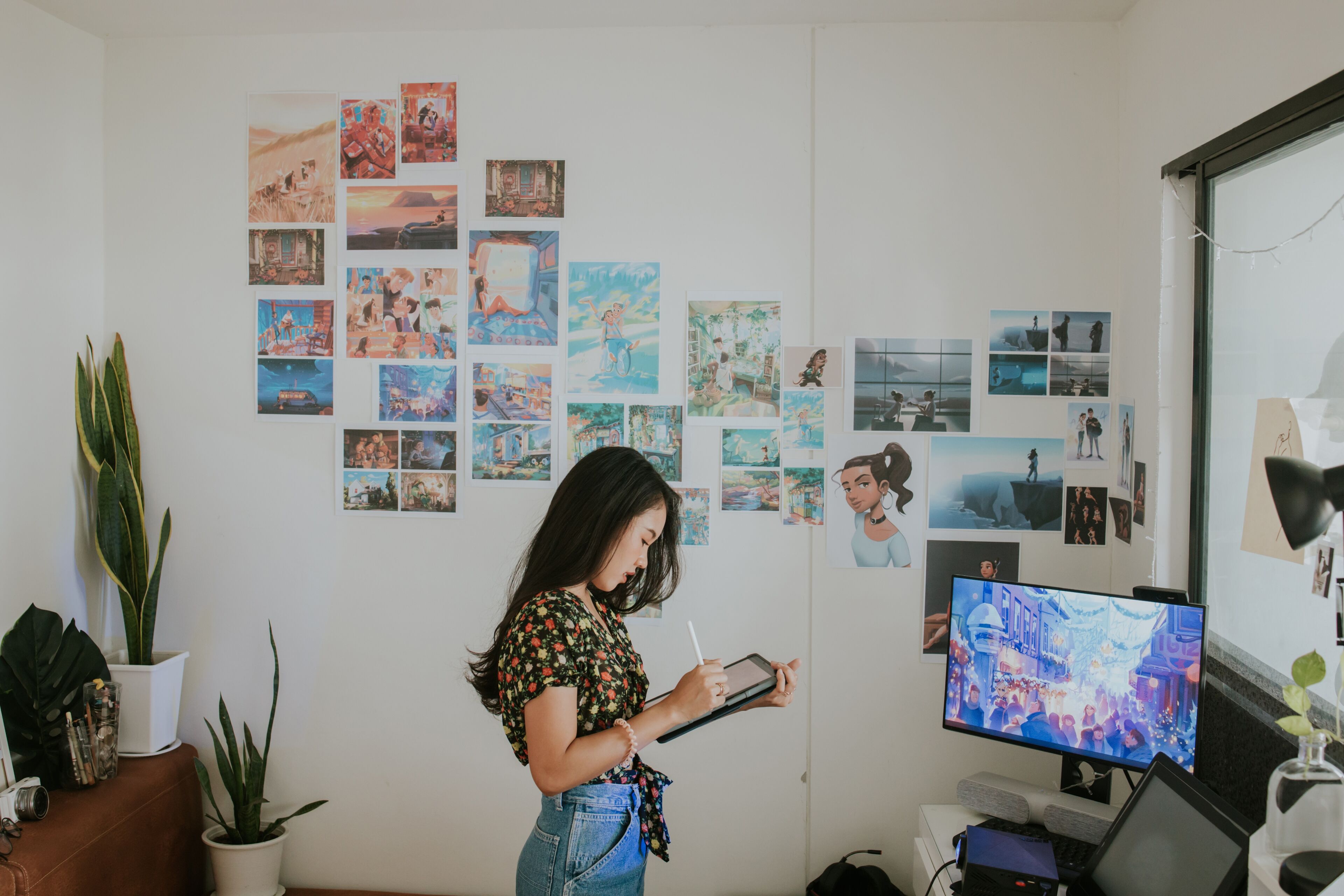 A focused artist sketches on a digital tablet in a creative workspace adorned with colorful animation artwork.