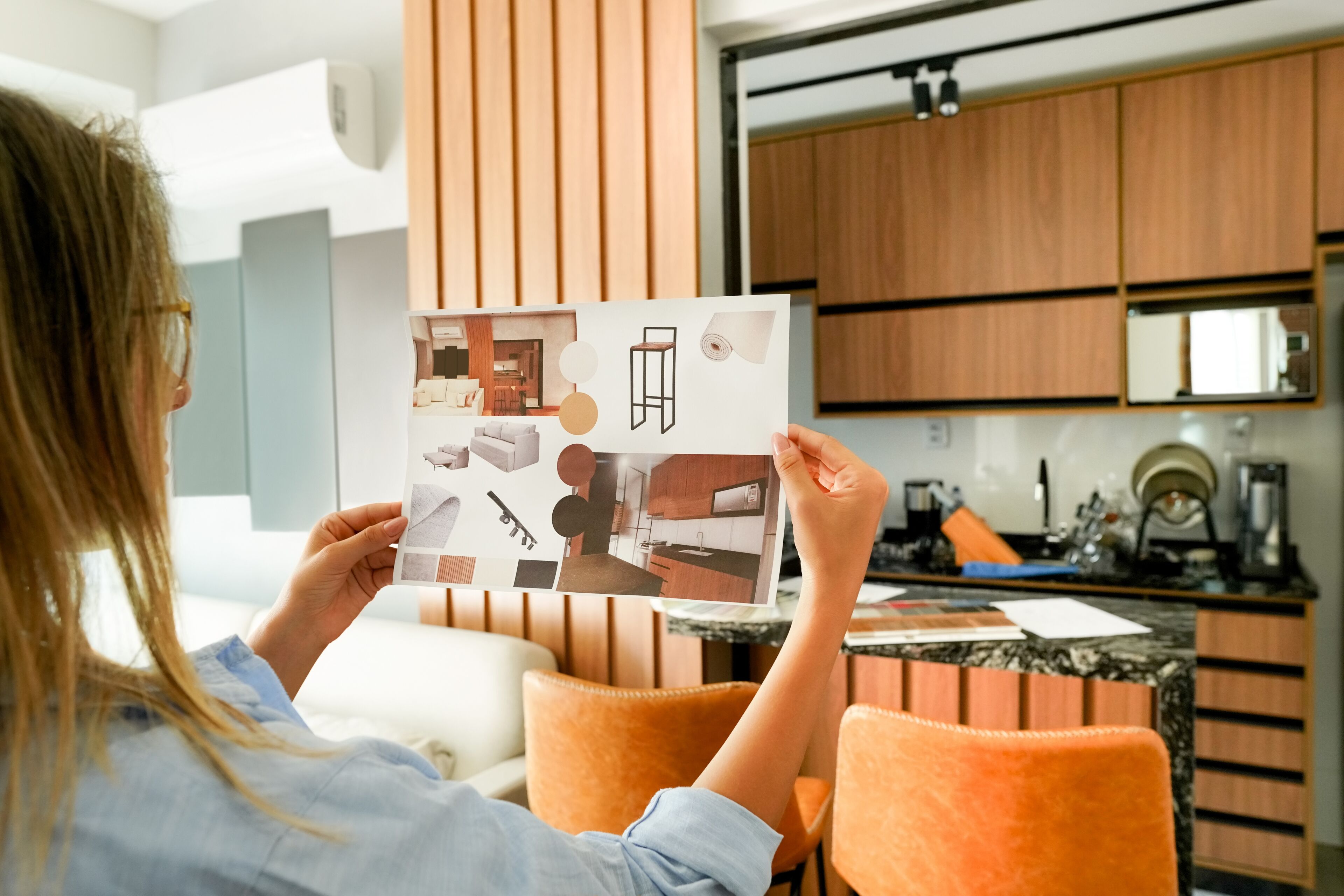 ImageA person examines a mood board containing various interior design elements for a home renovation project.