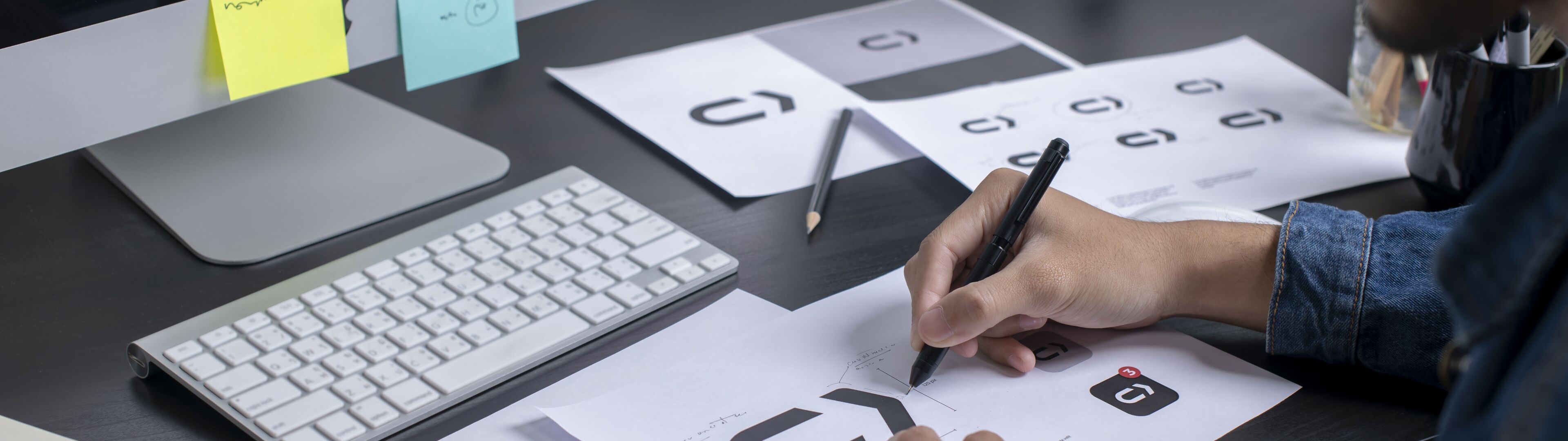 A graphic designer meticulously refining a logo design in a well-organized workspace.