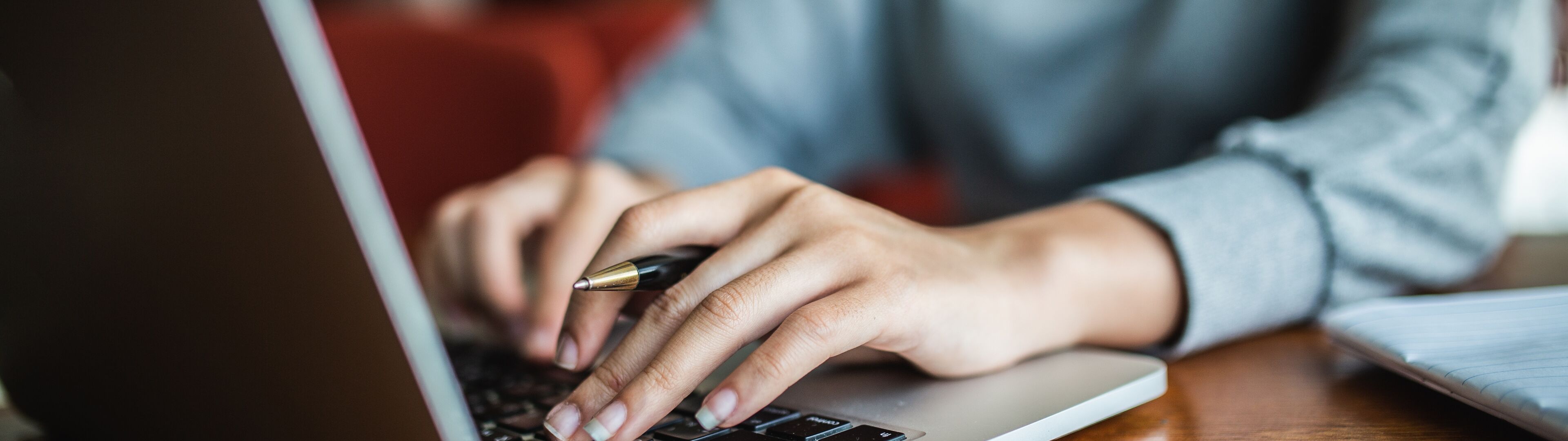 A close-up of a person's hands typing on a laptop keyboard, suggesting a professional setting.