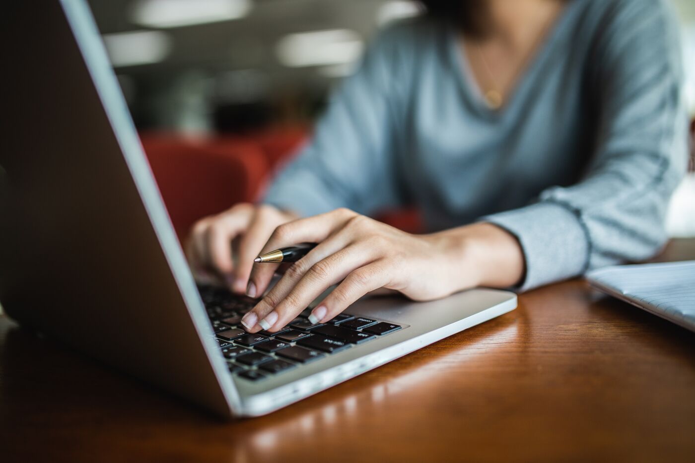 A close-up of a person's hands typing on a laptop keyboard, suggesting a professional setting.