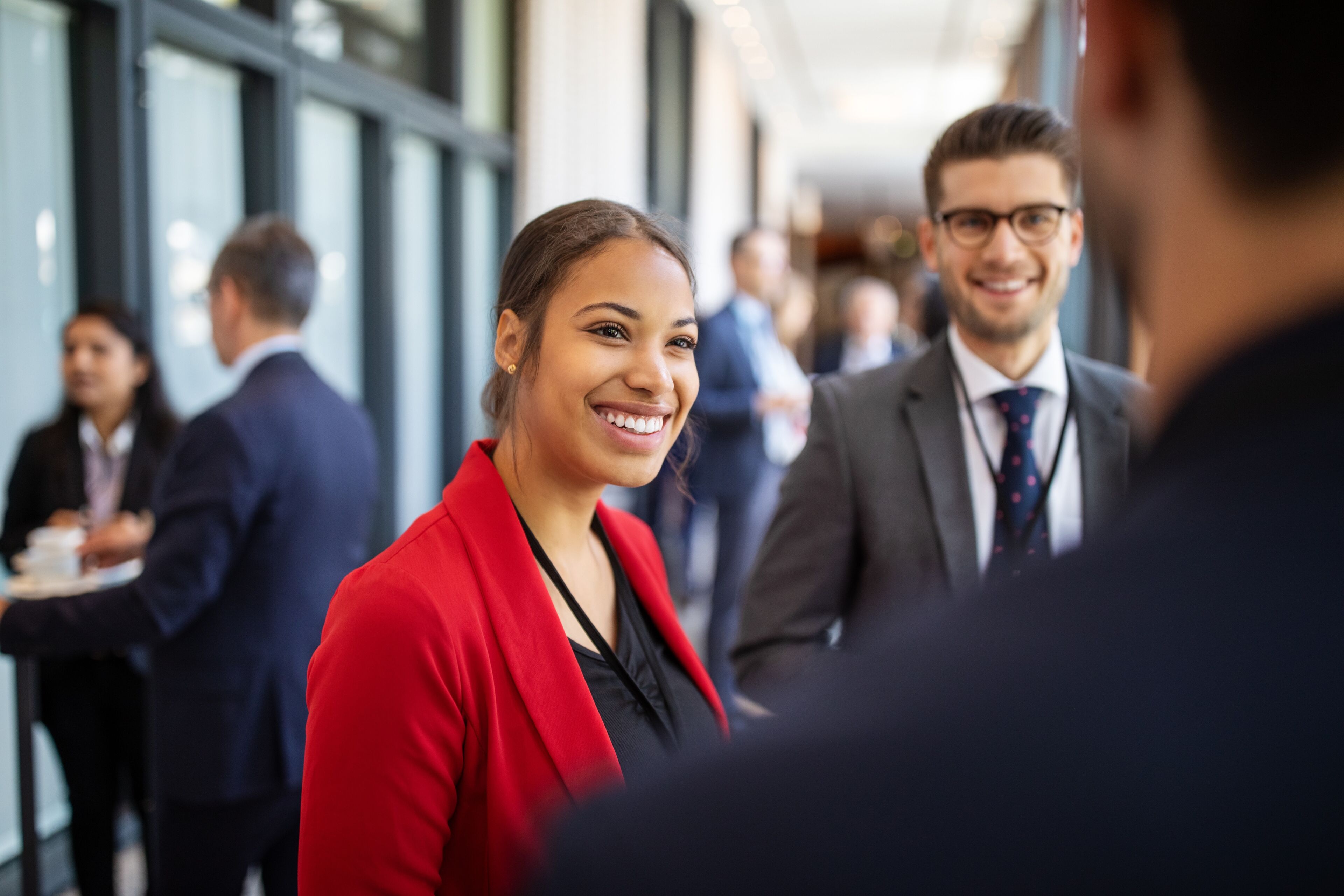 Smiling professionals engage in conversation at a networking event, with a focus on interpersonal connection.

