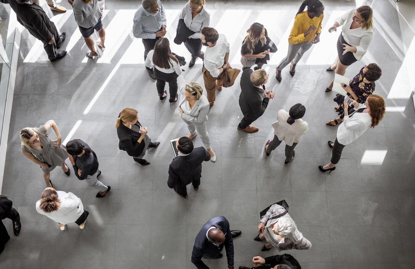 Overhead view of professionals in business attire engaging in conversation at a corporate networking event, highlighting dynamic interactions.