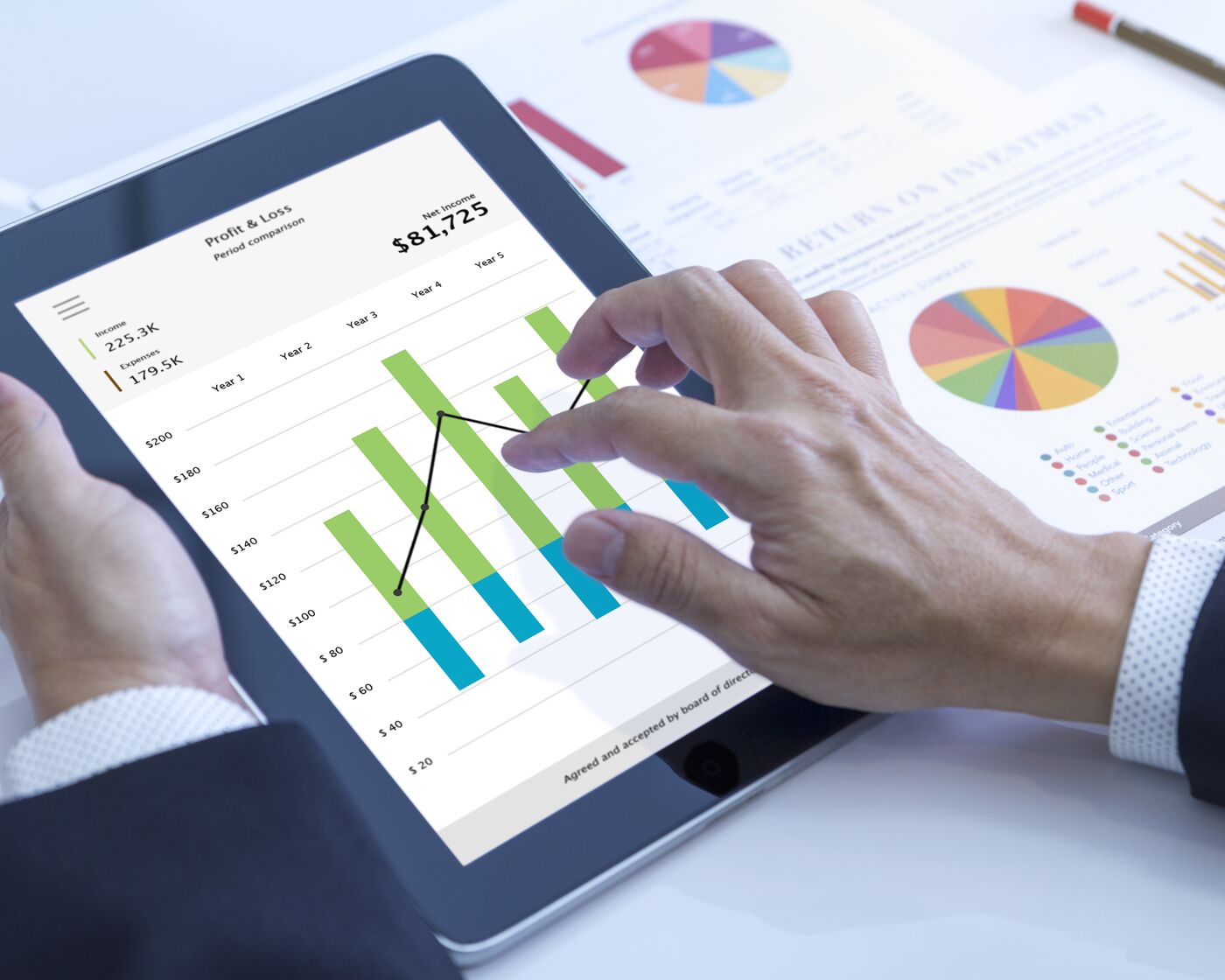 Close-up of hands analyzing financial data on a tablet.