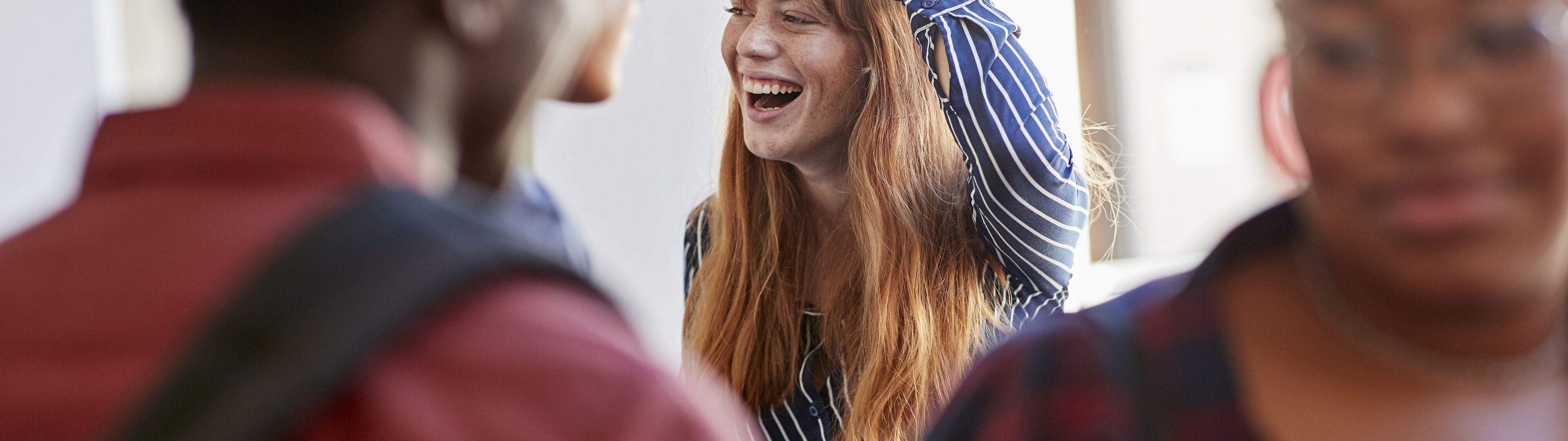 Una dona riu alegrement, mà al cap, en una trobada d'amics.