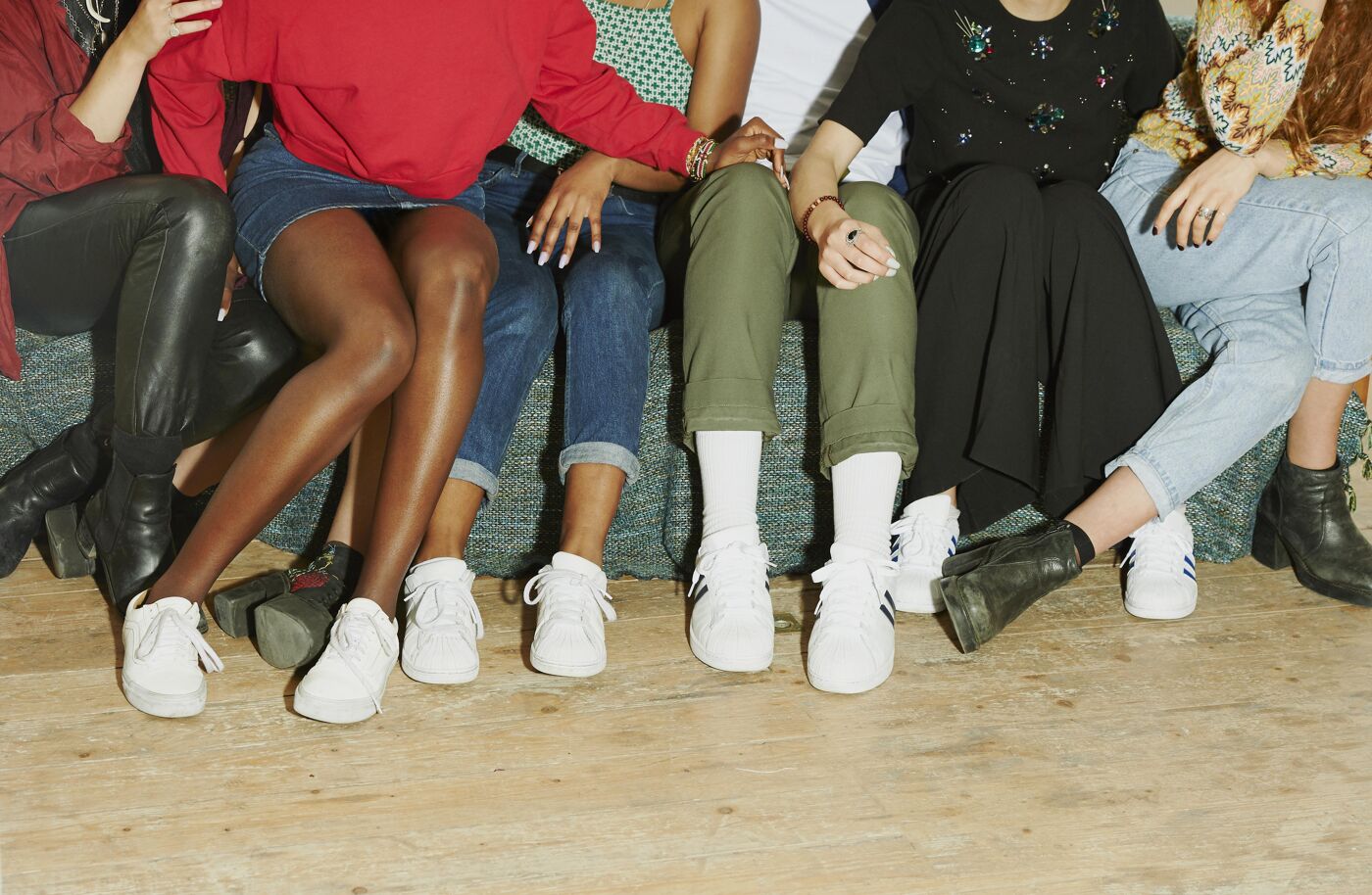 Close-up view of a group of young women sitting together, wearing sneakers and casual clothing.