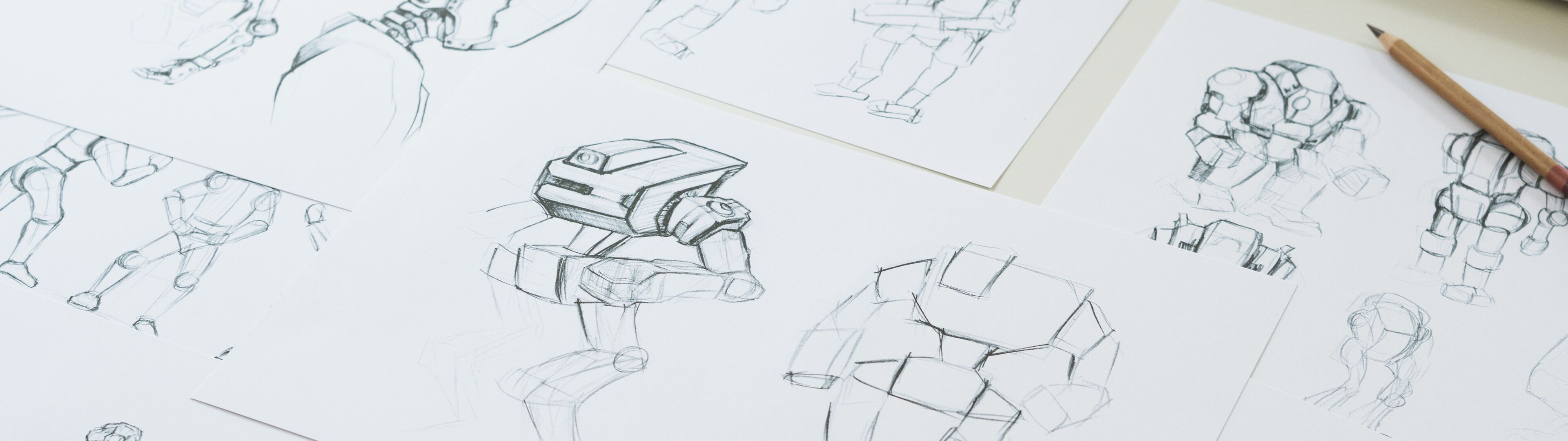 Multiple sketches of a robot character in various poses spread across a designer's workspace, illustrating the concept development process.