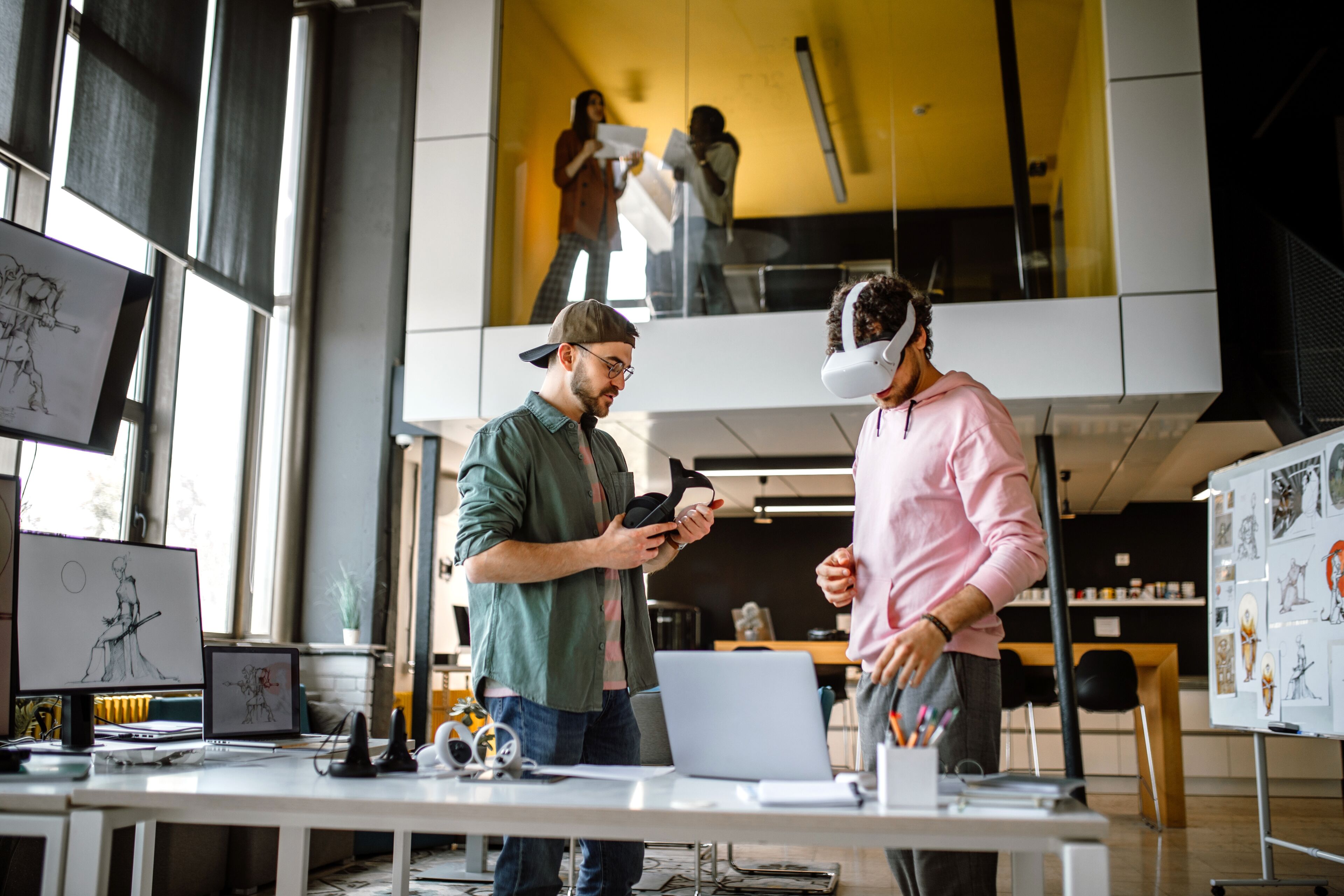 Deux concepteurs collaborent en utilisant la technologie VR dans un studio créatif avec des croquis et des modèles autour d'eux.