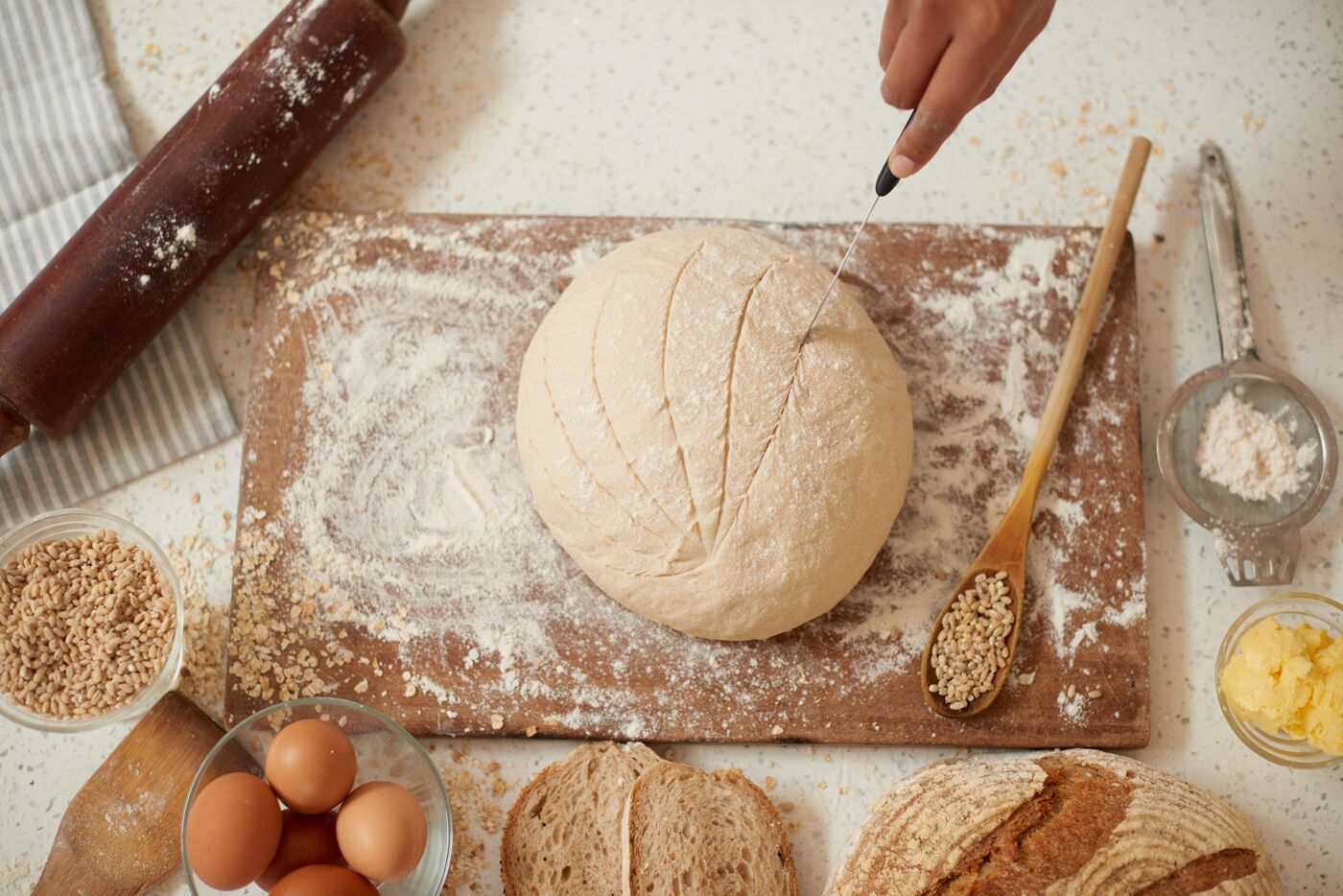 Baker's hands holding knife giving shape to dough. sprinkled with flour close-up along with some eatable items. yeast dough ready for pizza. Ingredients to make a tasty pizza. Recipe for bread. 