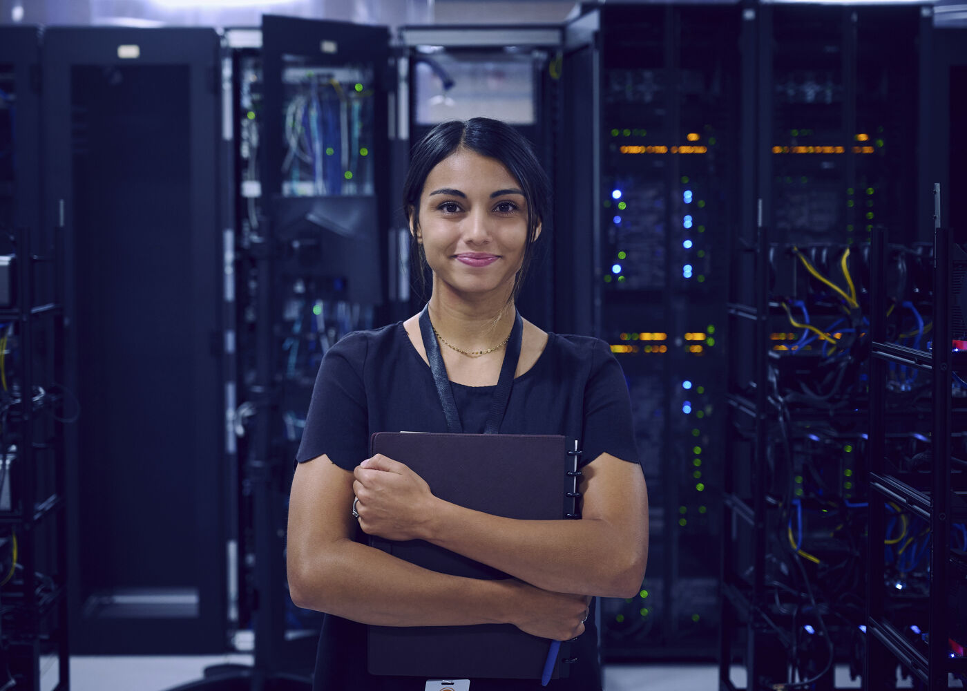 A confident network engineer with a clipboard stands before a backdrop of server racks, representing the human element in technology.