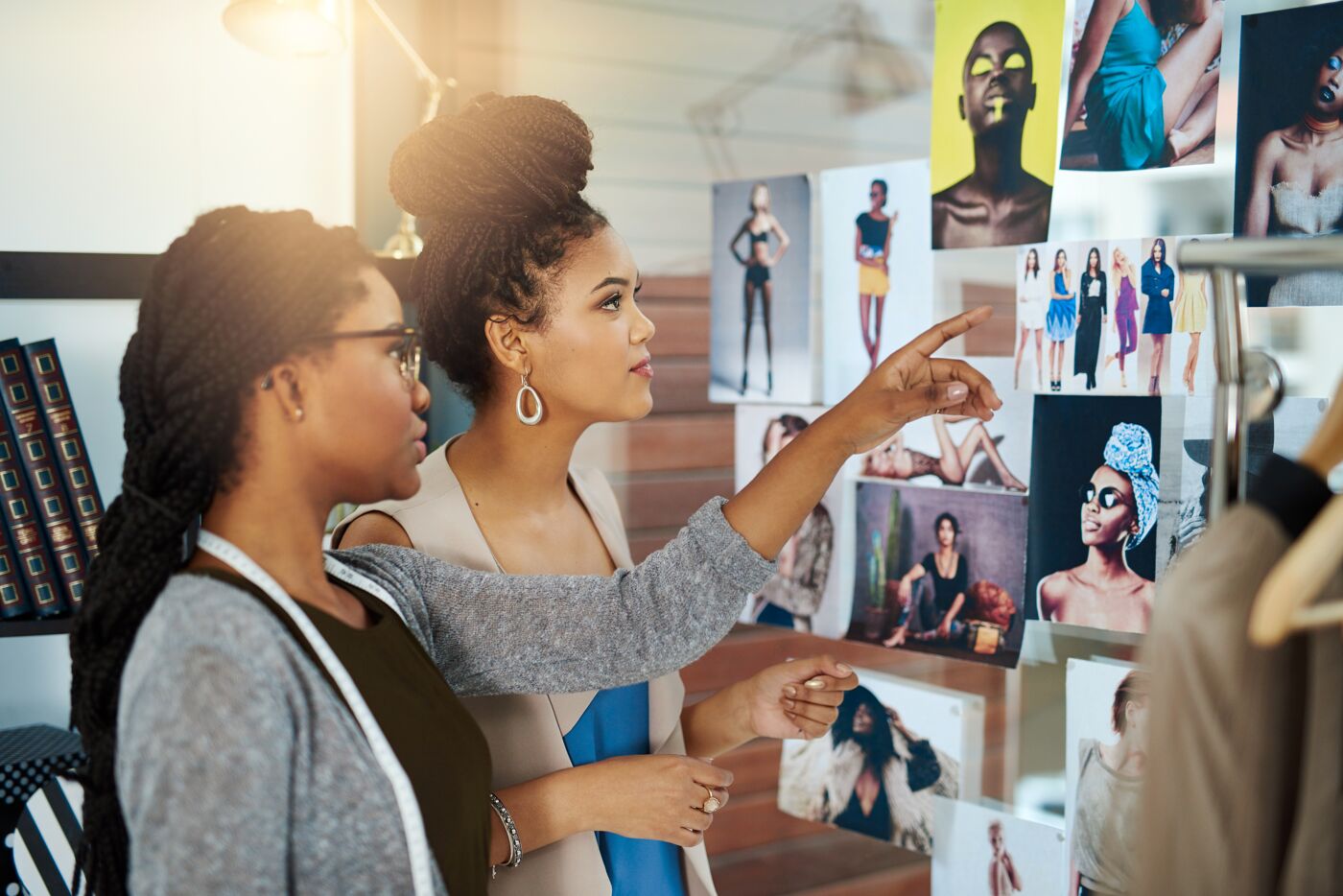 Two fashion designers critically evaluating a selection of photographs in a studio.