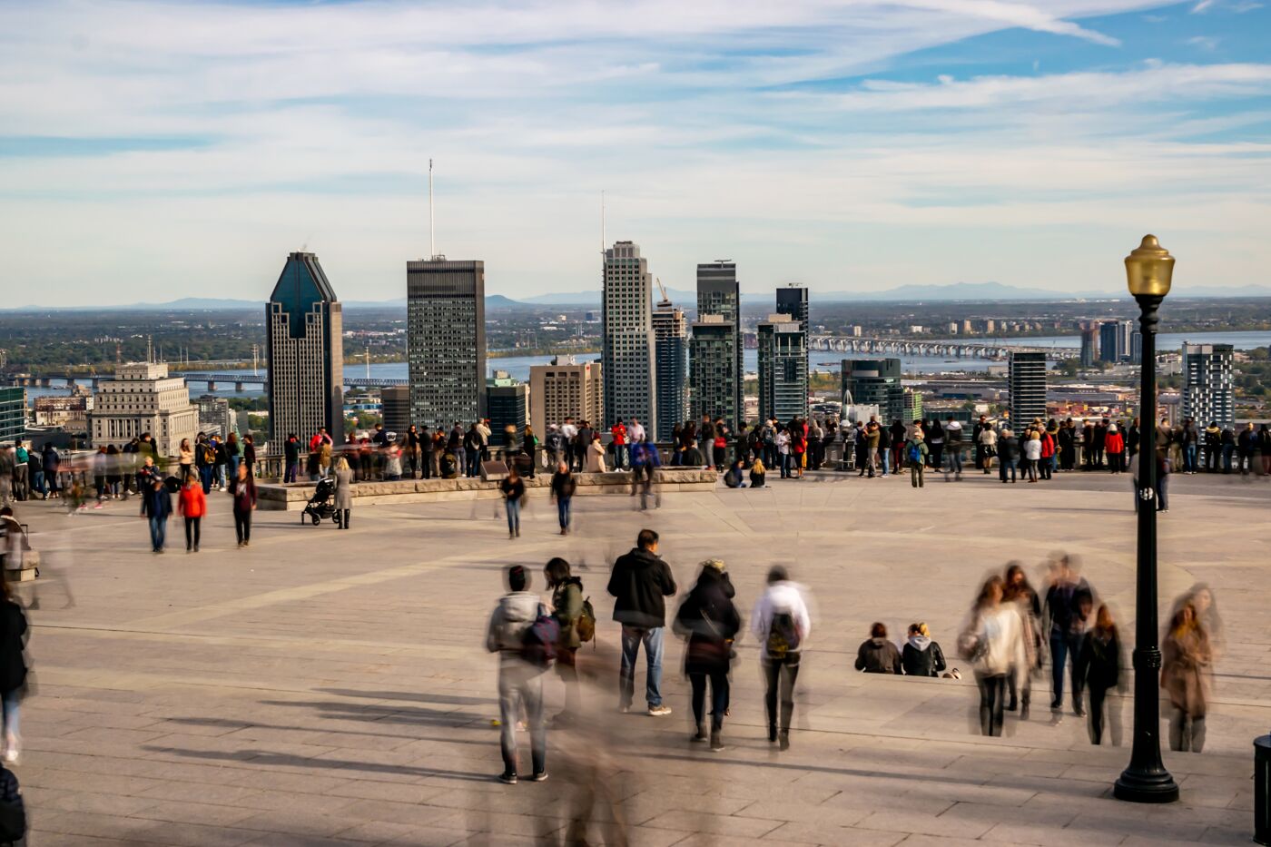 A dynamic scene at a popular viewpoint in Montreal, where crowds gather to enjoy the sweeping views of the cityscape and distant landscapes.