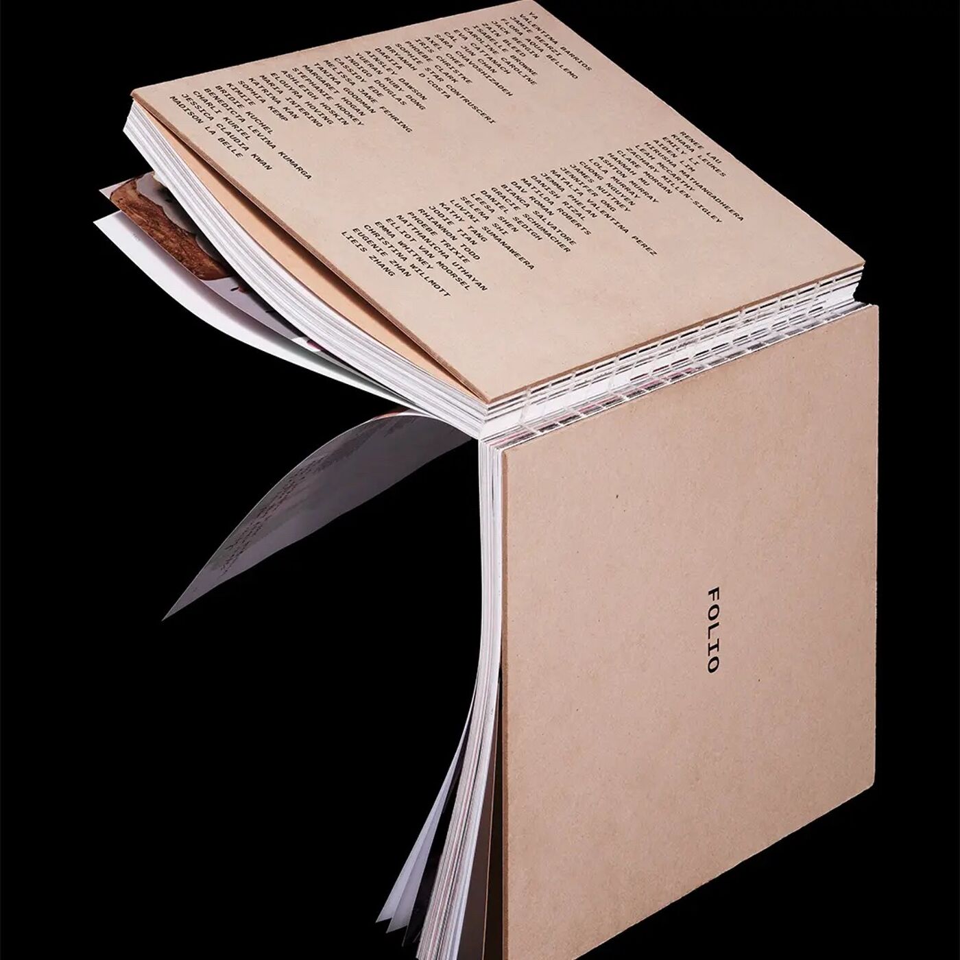 An open book with brown paper pages, featuring printed text and some images, set against a black background. The word "FOLIO" is visible on the cover.