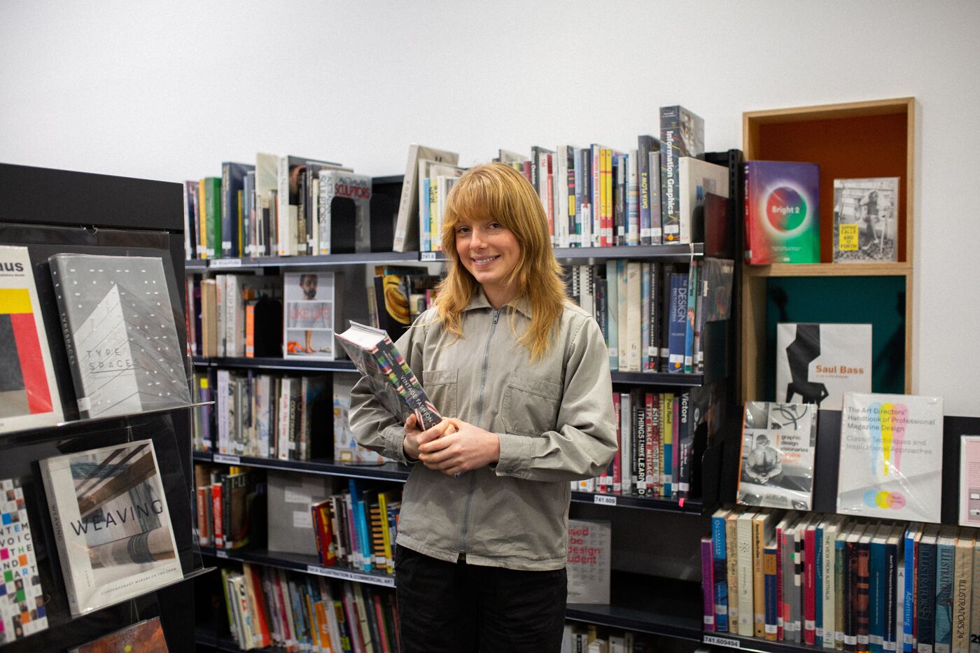 A cheerful woman browsing through a selection of books in a cozy bookstore.