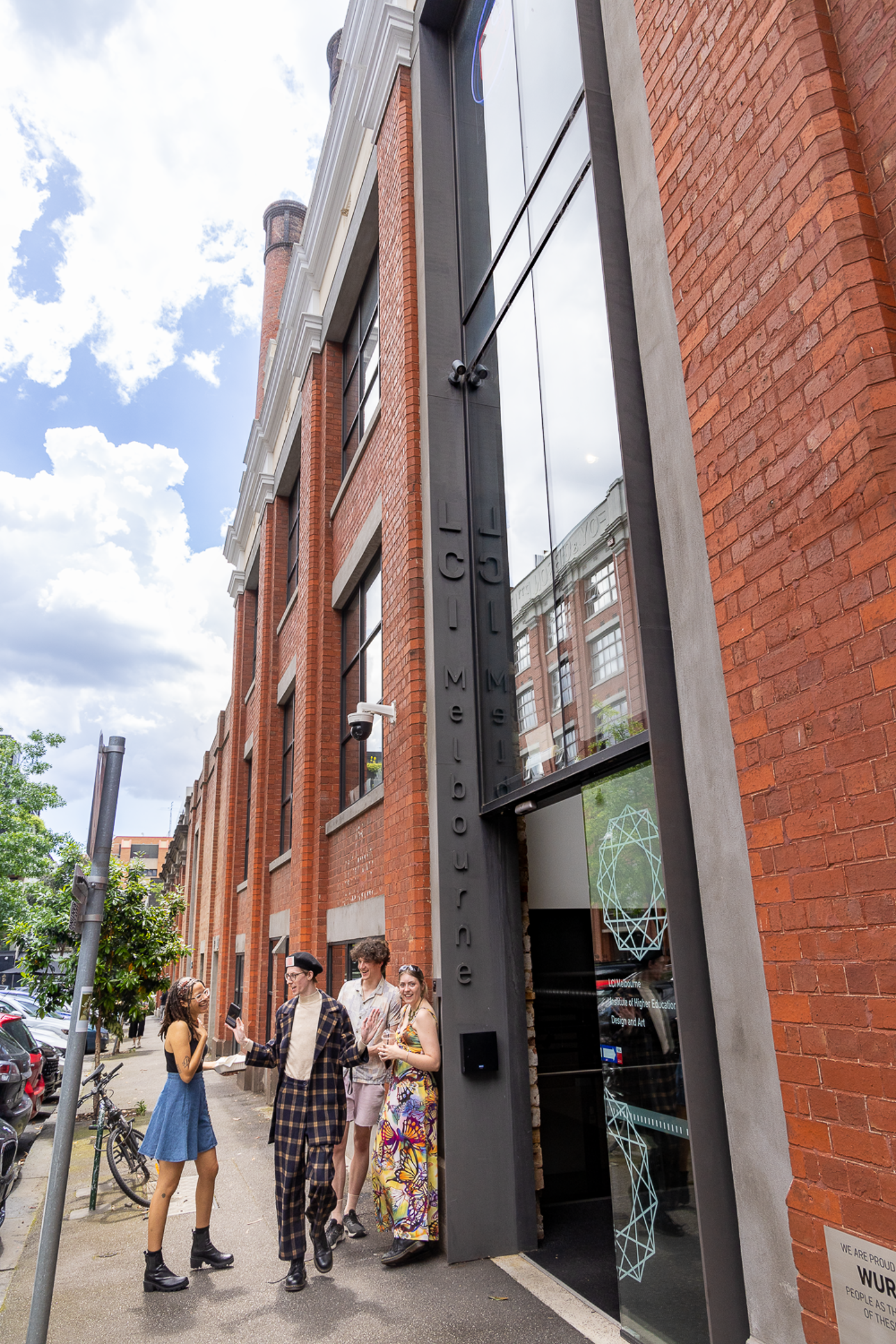 Fashionable pedestrians stroll by the entrance of a repurposed LCI Collingwood building, blending old and new.