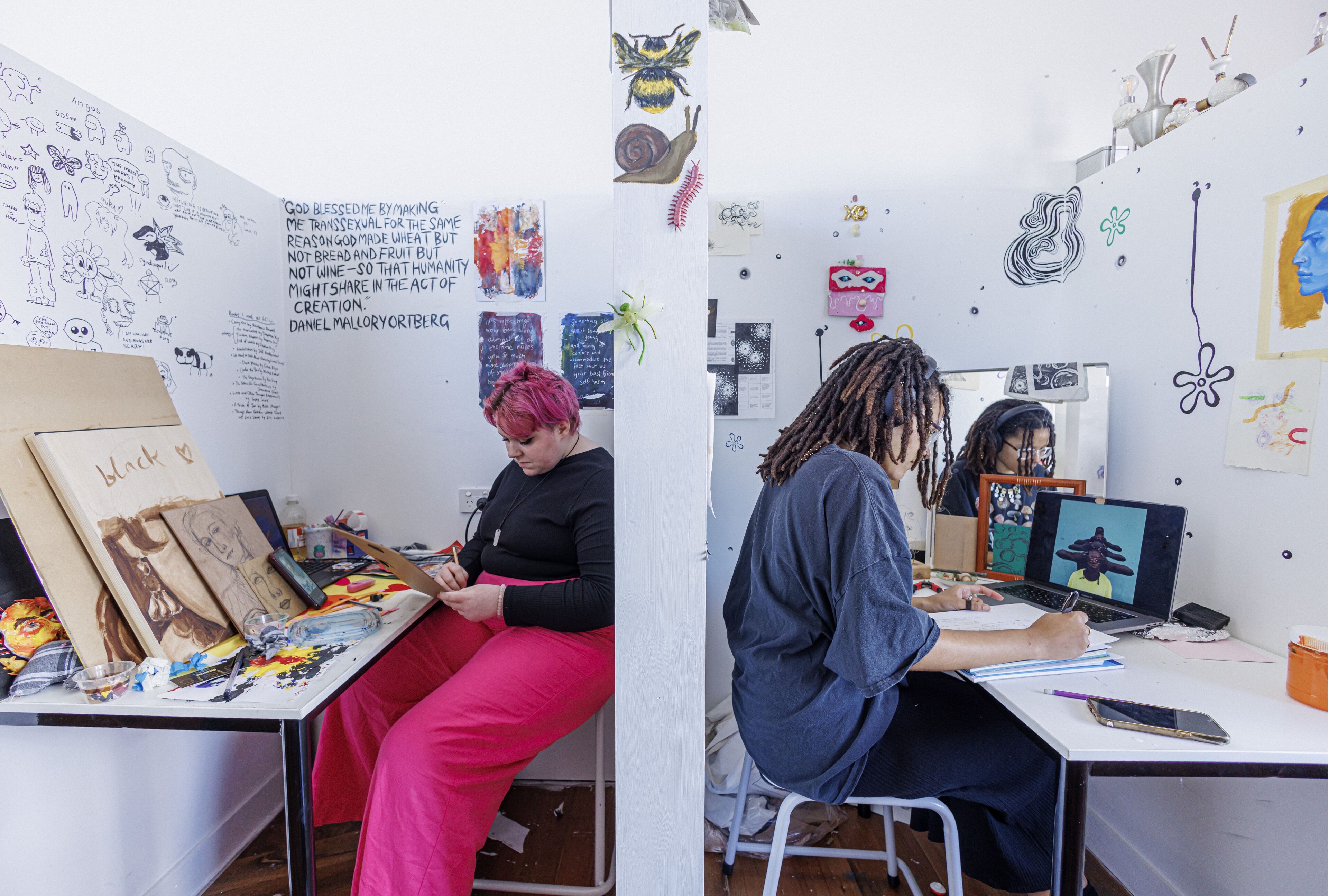 Two artists deeply engaged in their crafts in a studio adorned with artwork.