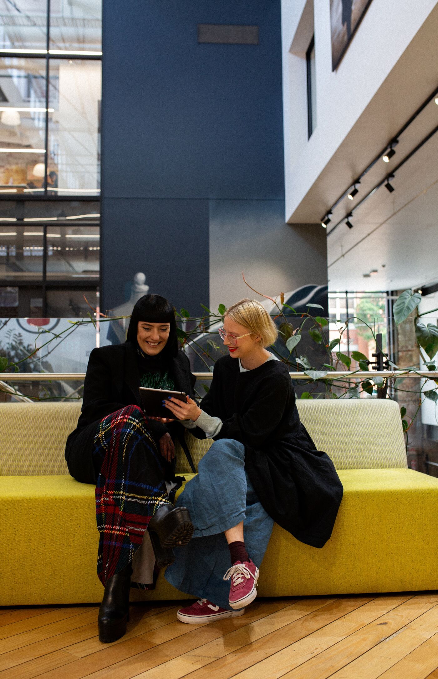 Two designers share a laugh while collaborating on a project in a vibrant, plant-filled studio space.