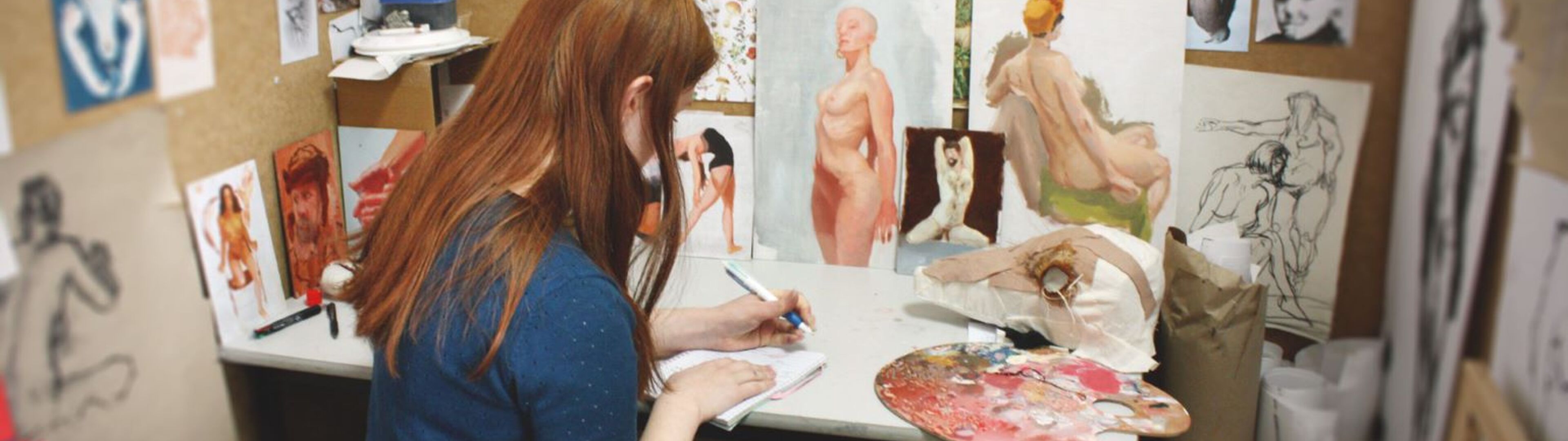 An artist lost in concentration sketches in her studio, her fiery hair mirroring the passion of her work.