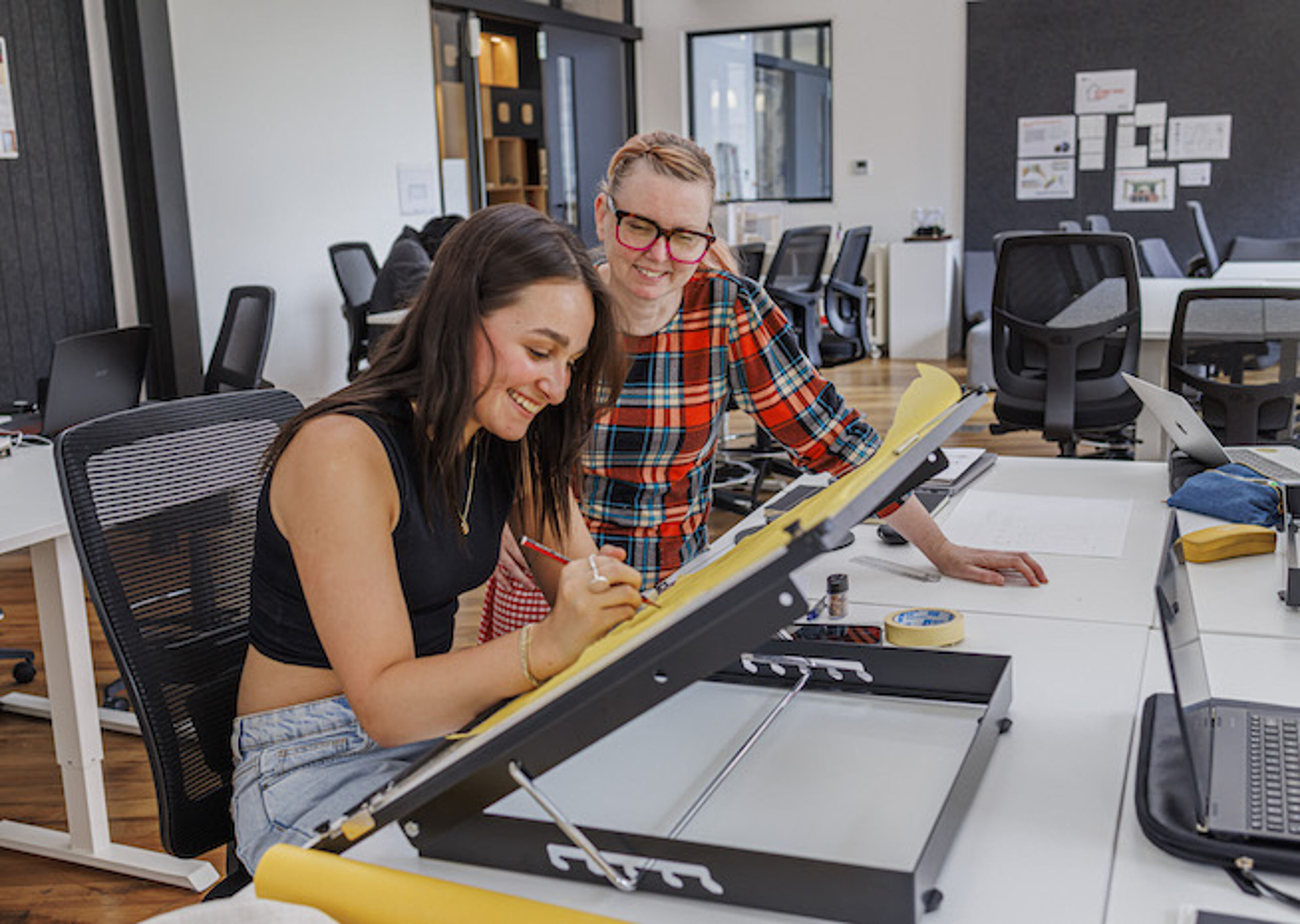 Two designers share a moment of joy while working on a project in a bright, modern office.