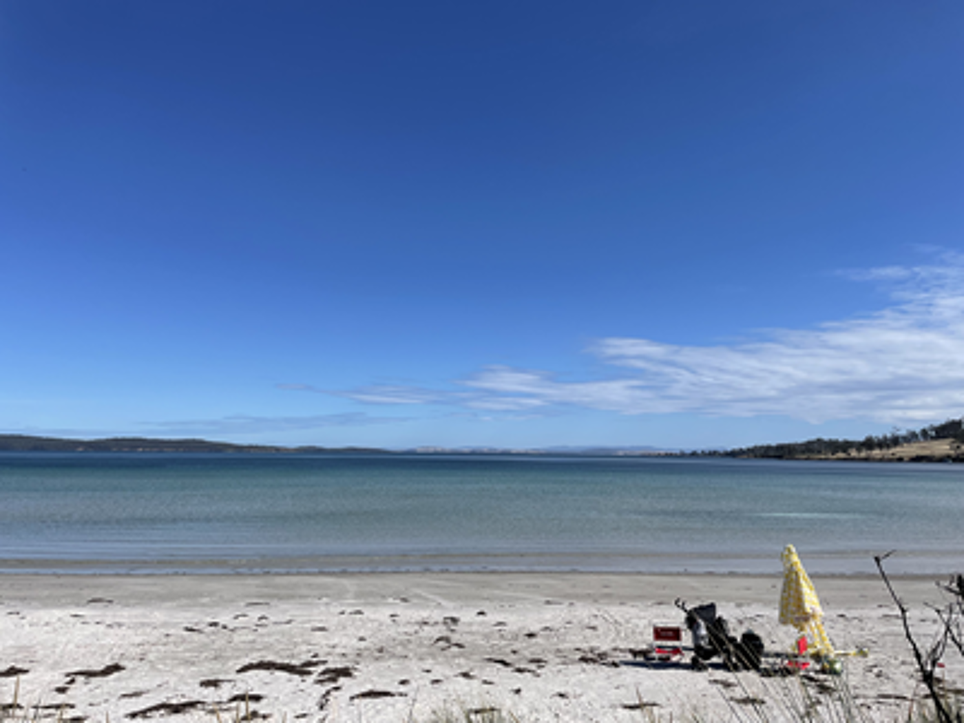 A tranquil beach scene with clear skies, inviting visitors to relax by the serene waters.