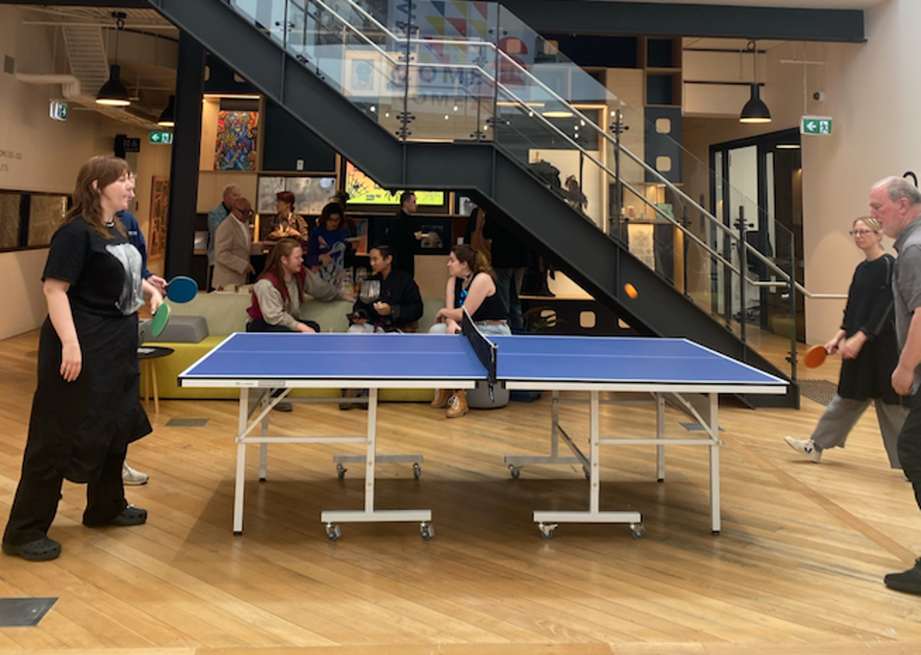 Colleagues enjoy a friendly game of table tennis in a vibrant, welcoming office space.