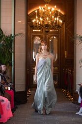 A model in a flowing gown strides confidently during a luxurious fashion show.